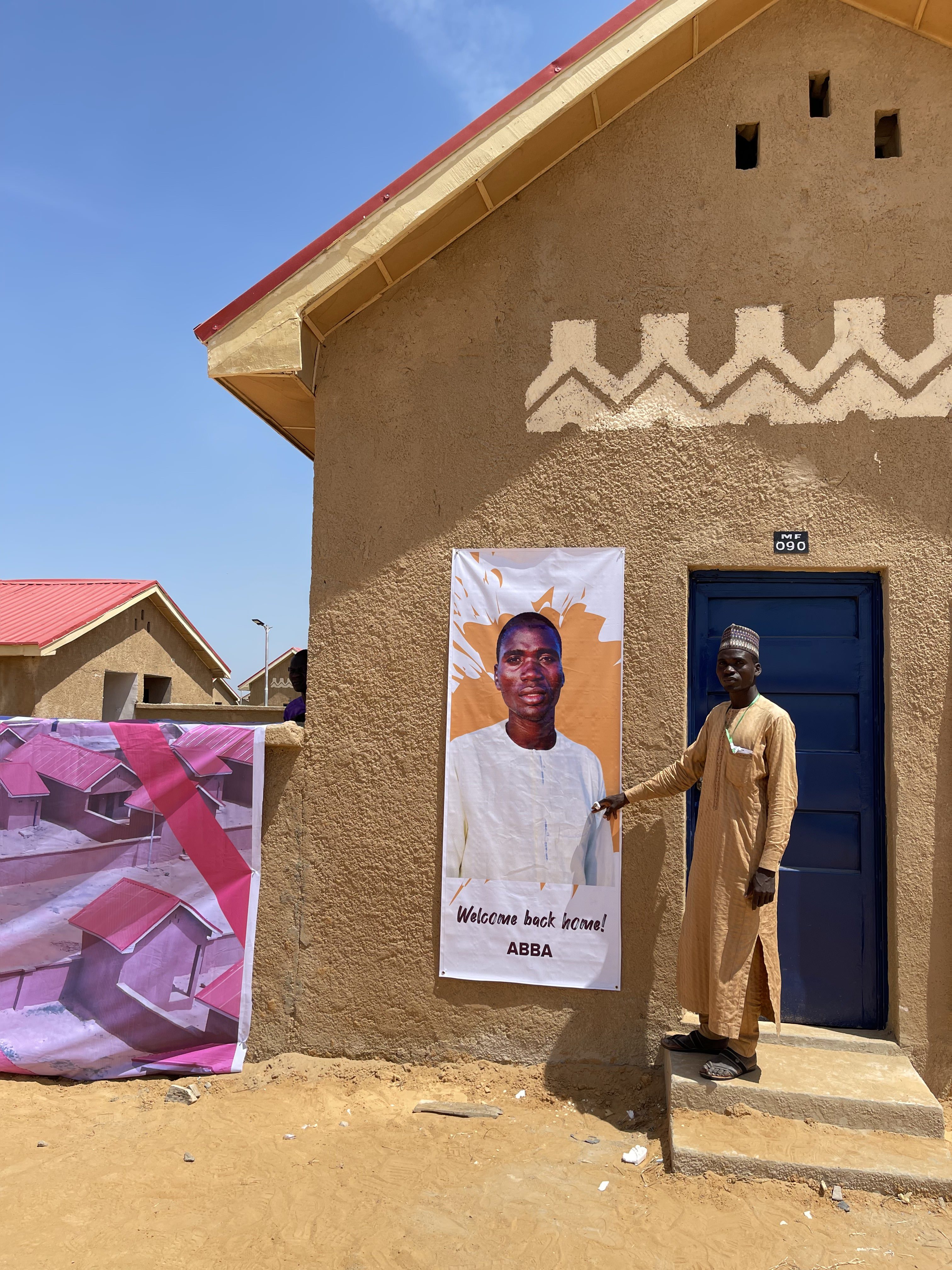 Saleh Abba stands in front of his new house in Ngarannam, Borno [Festus Iyorah/Al Jazeera]