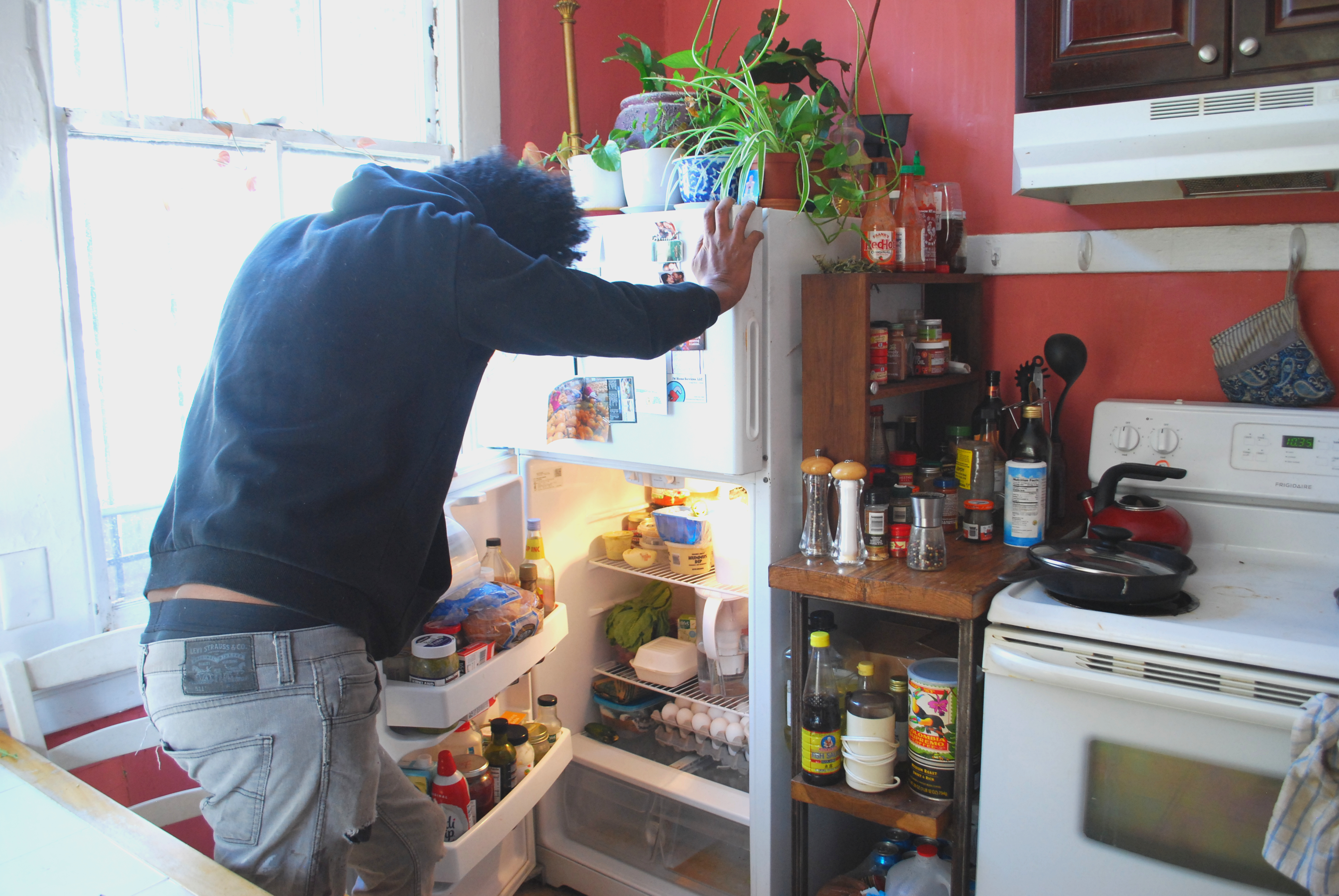 Aman looks through the refrigerator at Amber's house. As the cost of eating out has gone up 9 percent in the last year, he and Amber now almost always cook at home