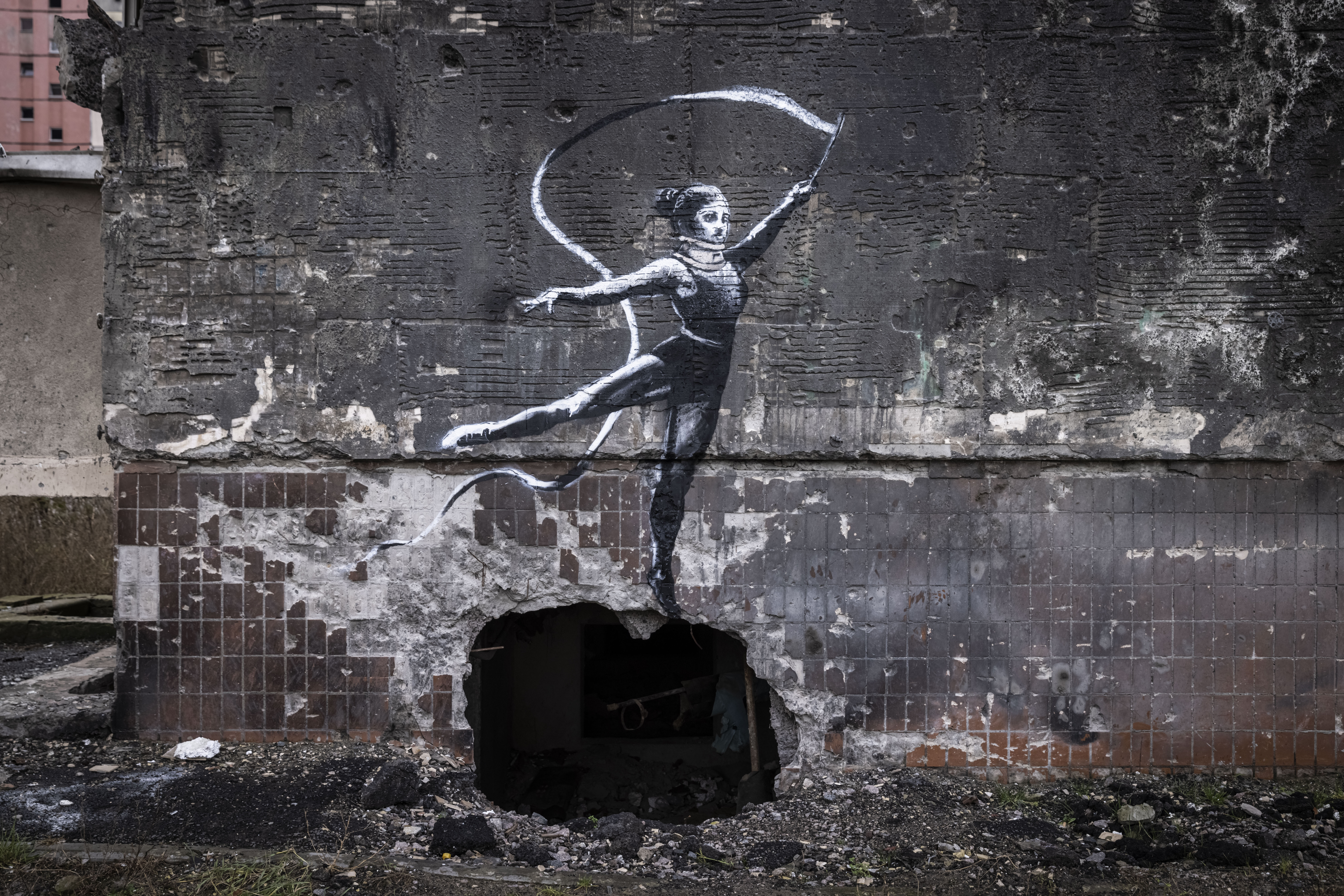 IRPIN, UKRAINE - NOVEMBER 11 Graffiti of a woman in a leotard and a neck brace waving a ribbon is seen on the wall of a destroyed building in Irpin on November 11, 2022 in Kyiv Region, Ukraine. Similar art work in the region sparked online speculation over whether the graffiti artist Banksy has been working in Ukraine. Irpin saw heavy fighting in the first few weeks of the conflict. Electricity and heating outages across Ukraine caused by missile and drone strikes to energy infrastructure have added urgency to preparations for winter. (Photo by Ed Ram/Getty Images)
