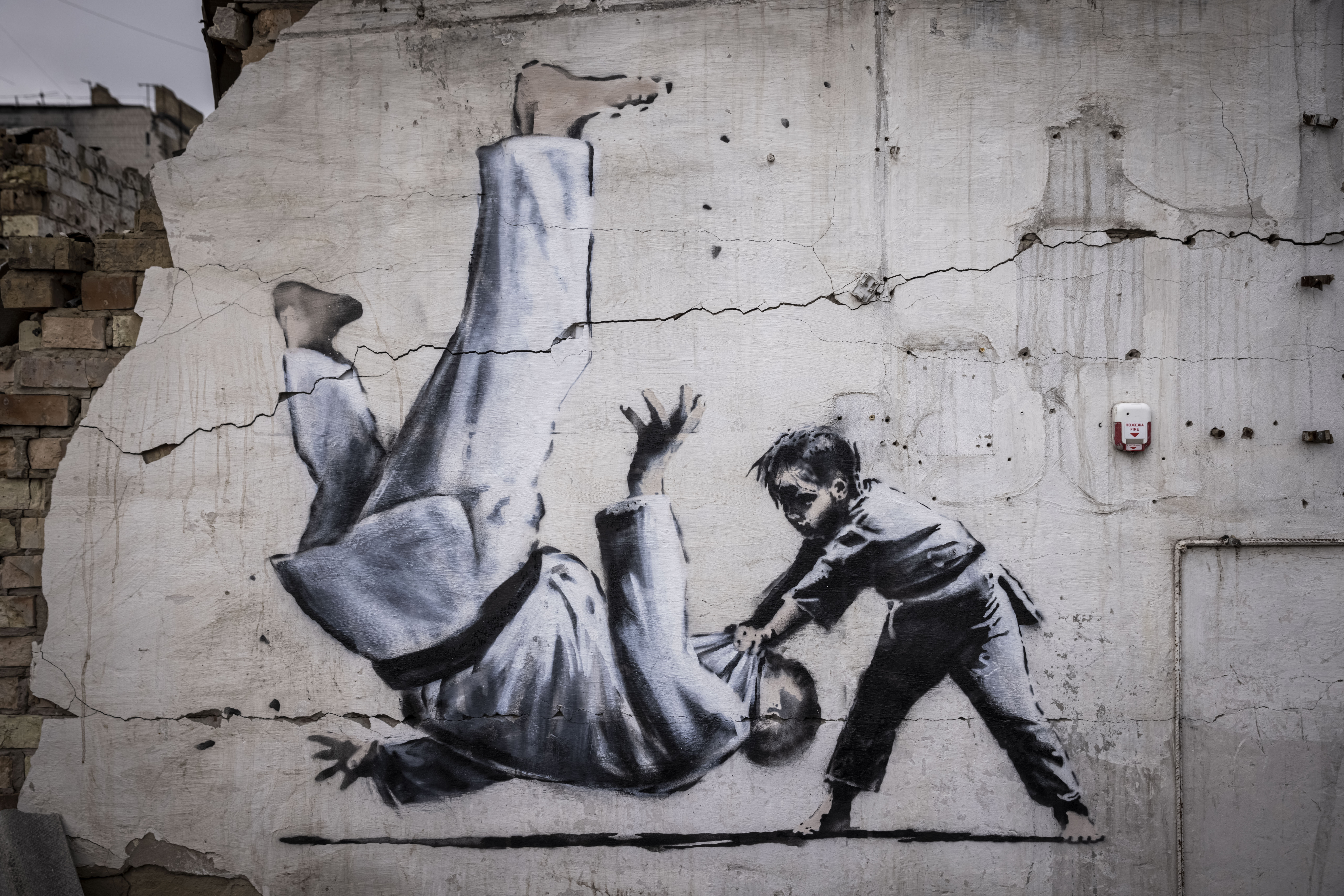 Graffiti of a child throwing a man on the floor in judo attire is seen on a wall amid damaged buildings in Borodyanka