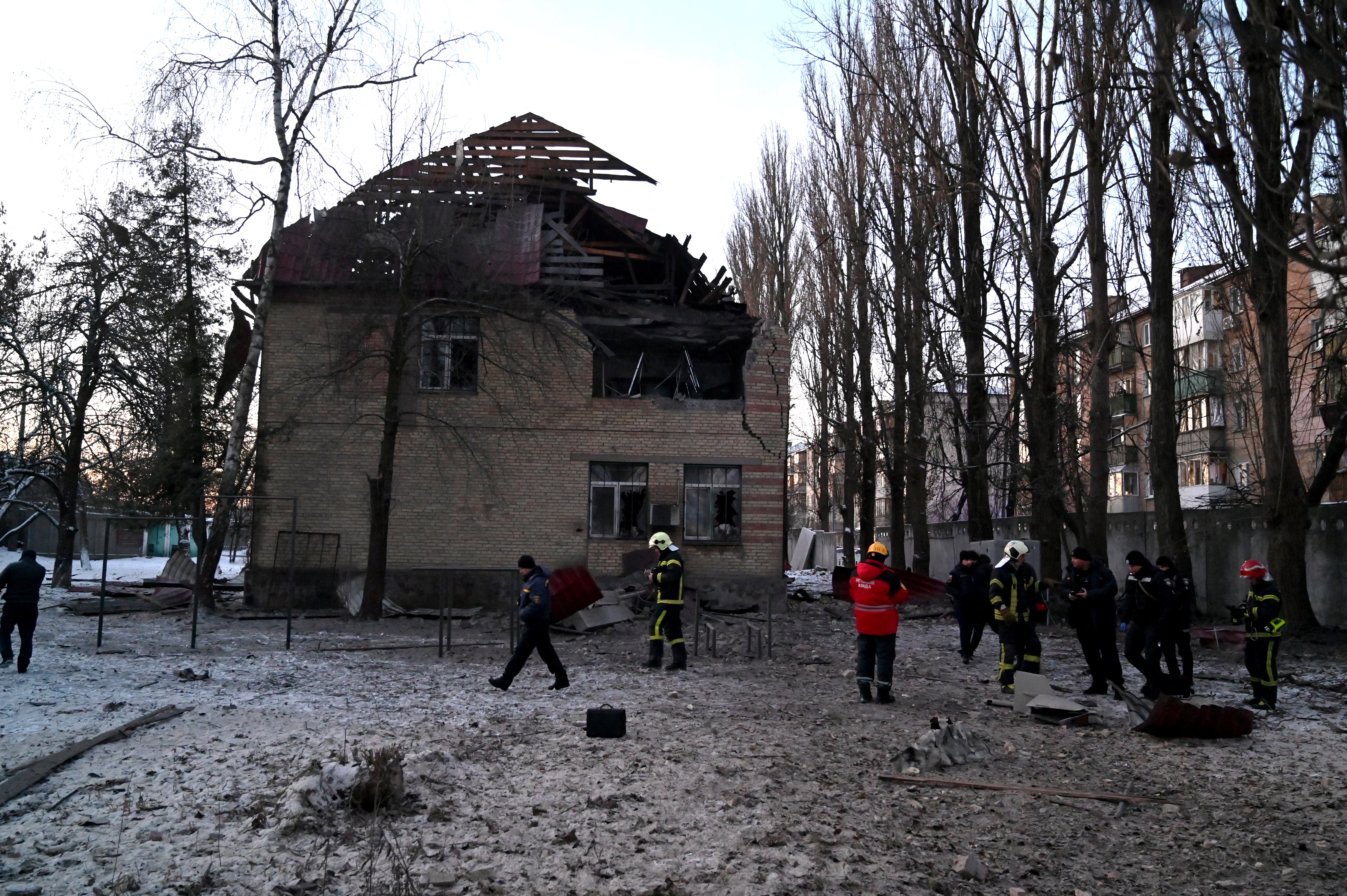 Rescuers and police experts examine the remains of a drone following an attack on an administrative building in Kyiv