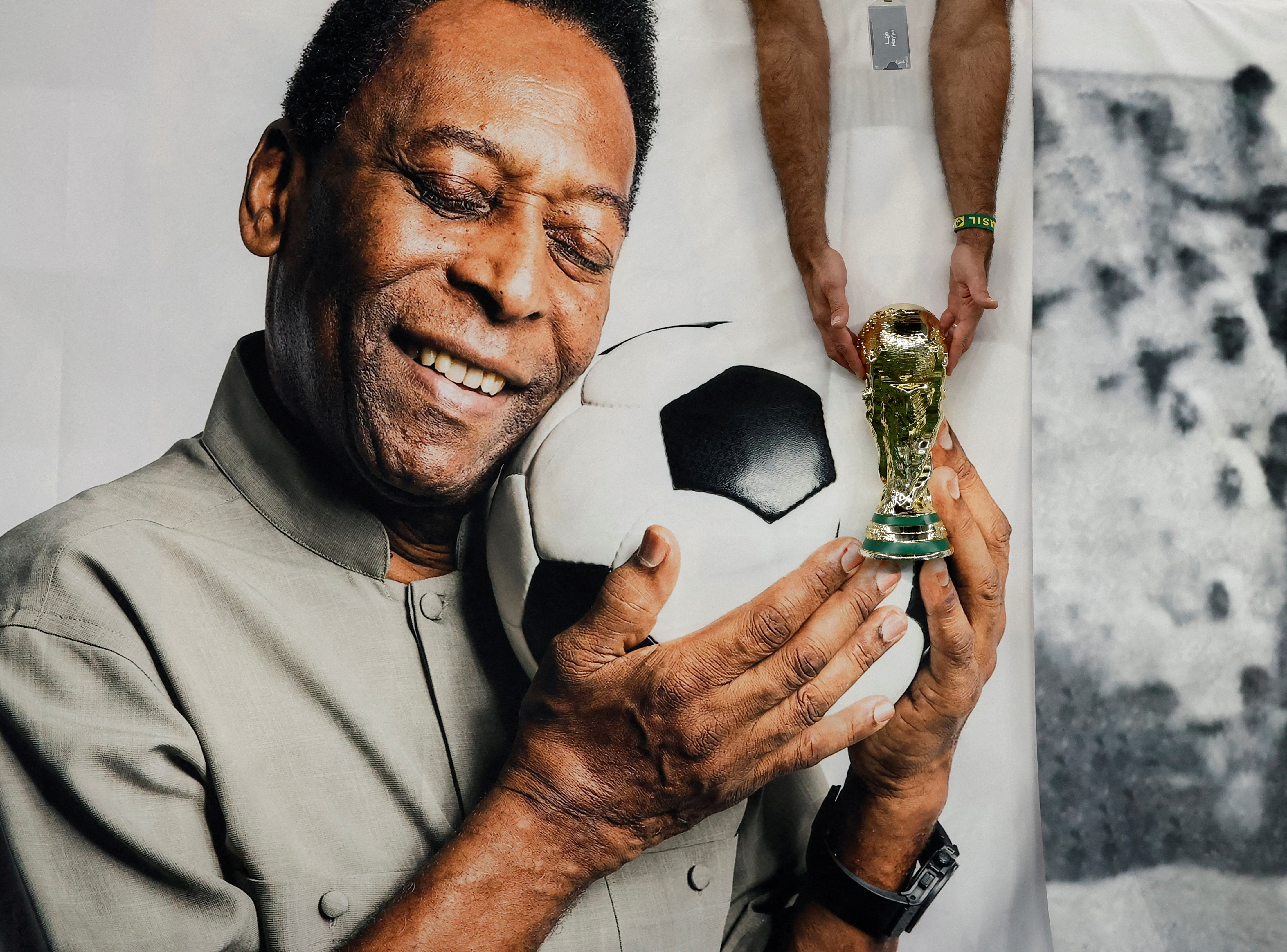 A Brazil fan holds a replica World Cup trophy in front of a banner of legendary Brazilian player Pele before the Cameroon vs Brazil match at Lusail Stadium, Lusail, Qatar