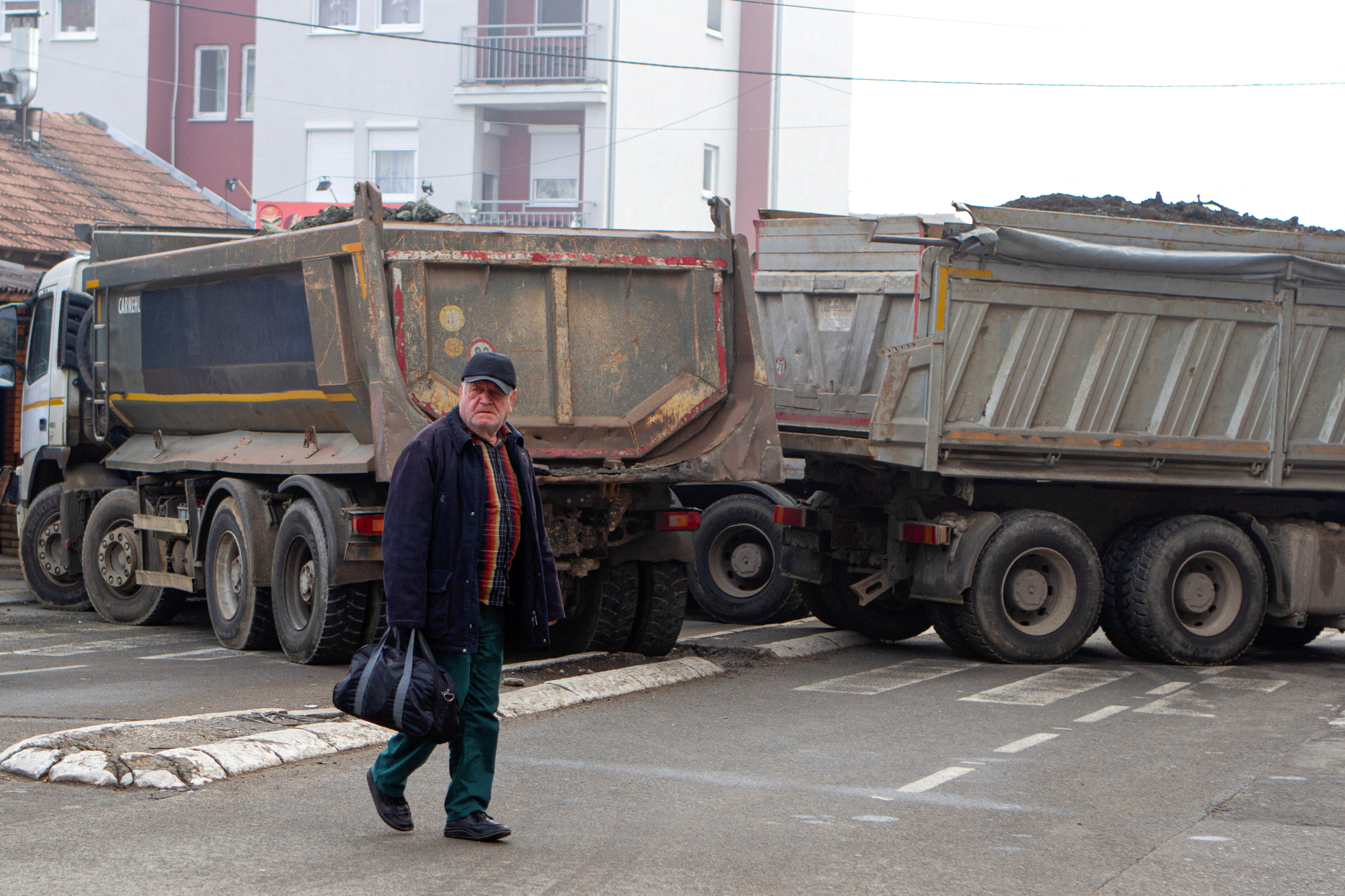 A man crosses a street near a roadblock in the northern part of the ethnically-divided town of Mitrovica, Kosovo, December 27, 2022. REUTERS/Miodrag Draskic
