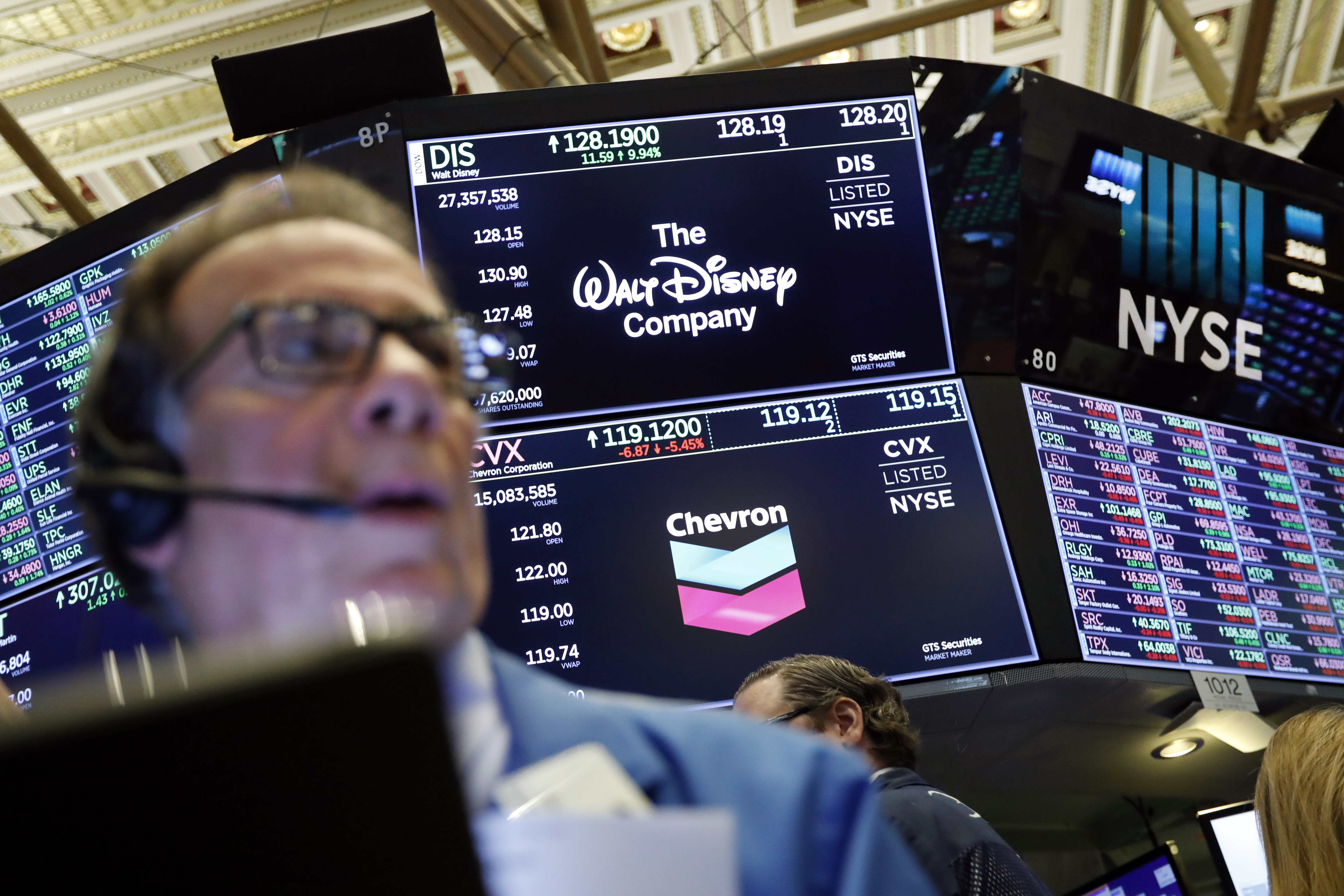The logos for The Walt Disney Company and Chevron appear above a trading post on the floor of the New York Stock Exchange, Friday, April 12, 2019. Energy companies rallied after Chevron said it would pay $33 billion to buy rival Anadarko Petroleum and Disney surged 12% to an all-time high after it announced plans to offer its own video streaming service. (AP Photo/Richard Drew)