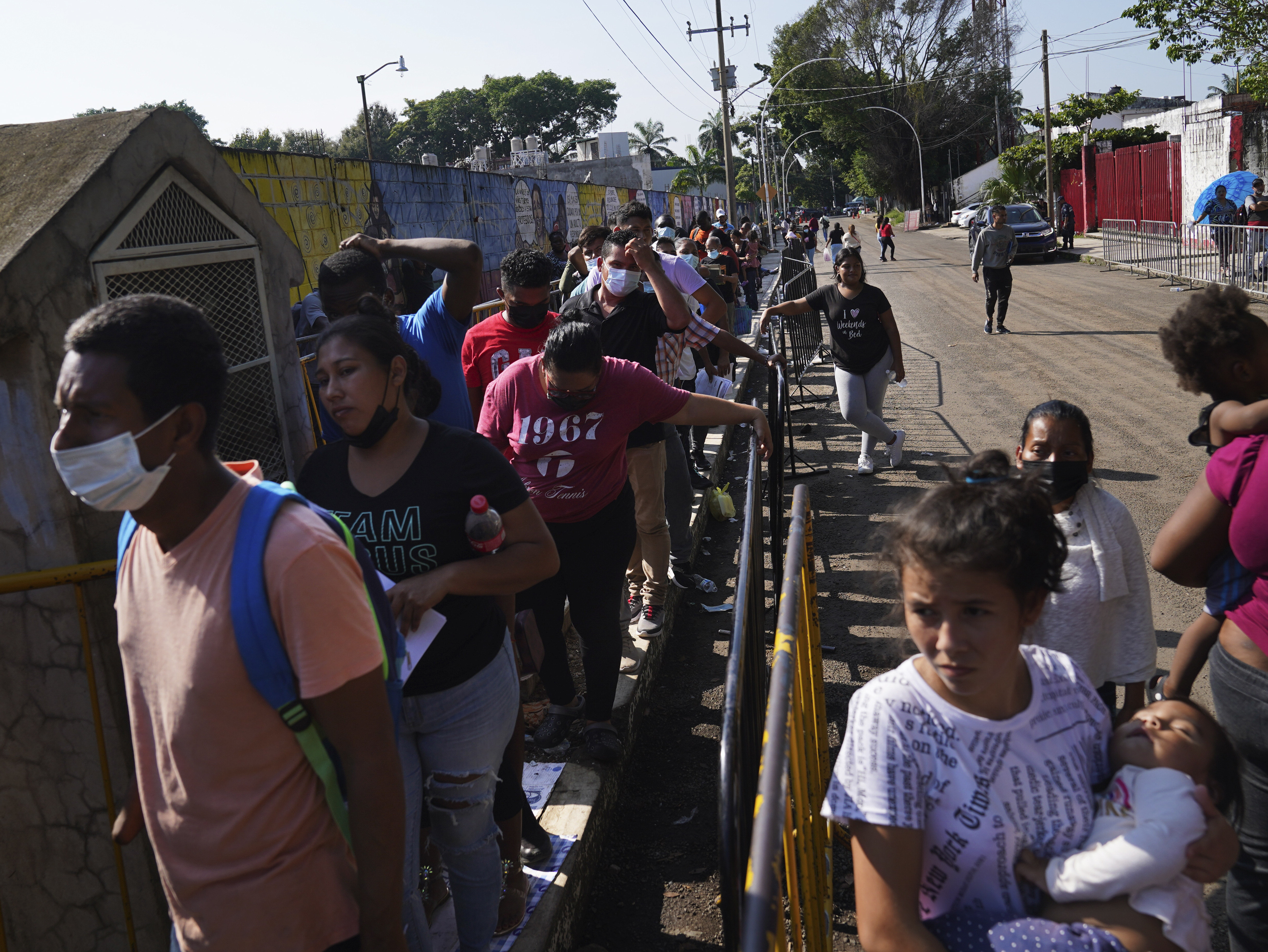 Migrants wait in line for their turn to apply for legal migration