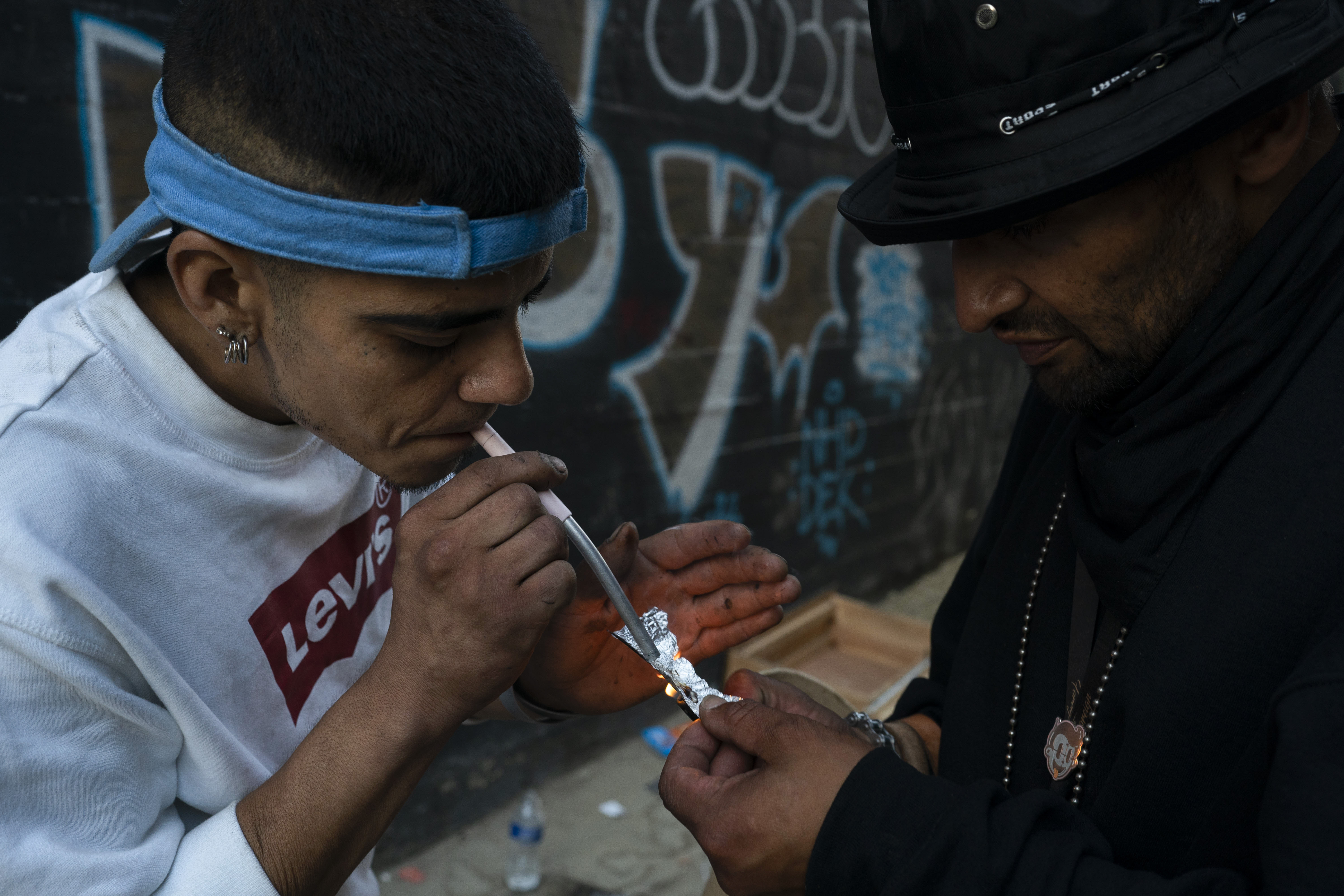two homeless people sharing a piece of fentanyl