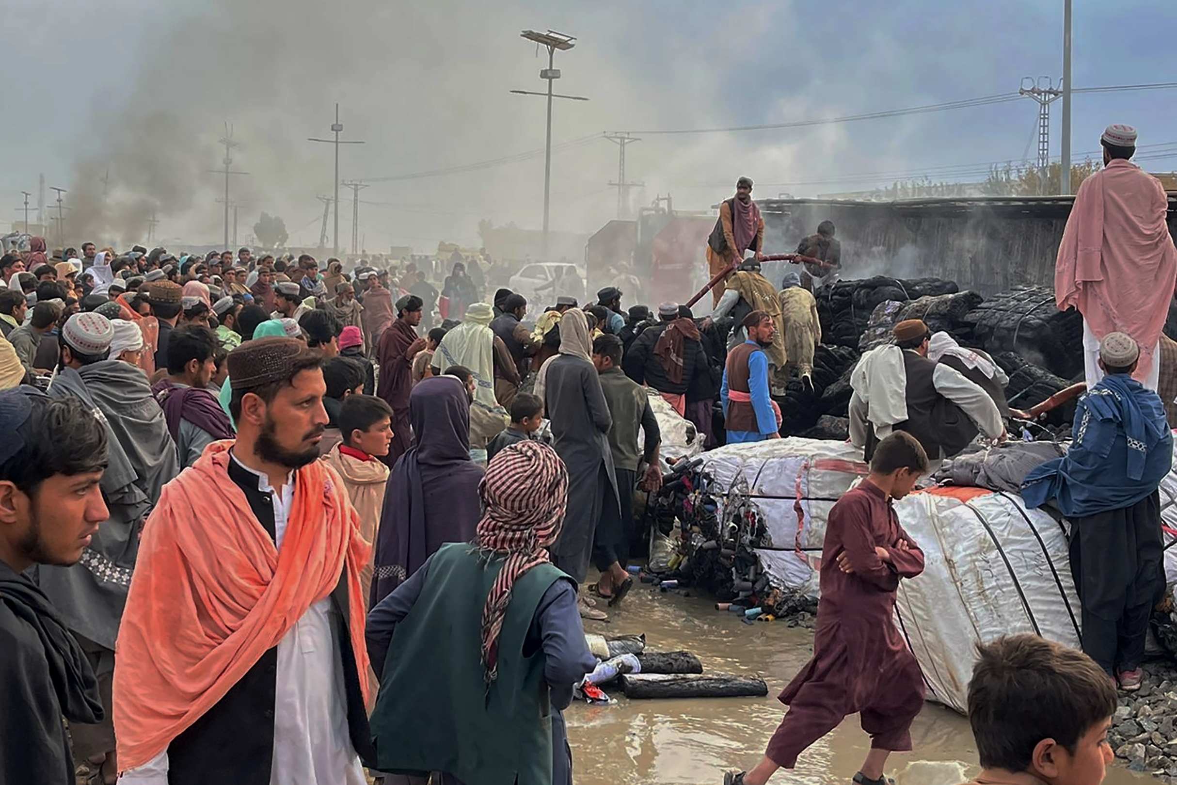People gather beside a truck burned by Afghan forces shelling in Chaman, a town in Pakistan’s southwest along the Afghan border [AP Photo]