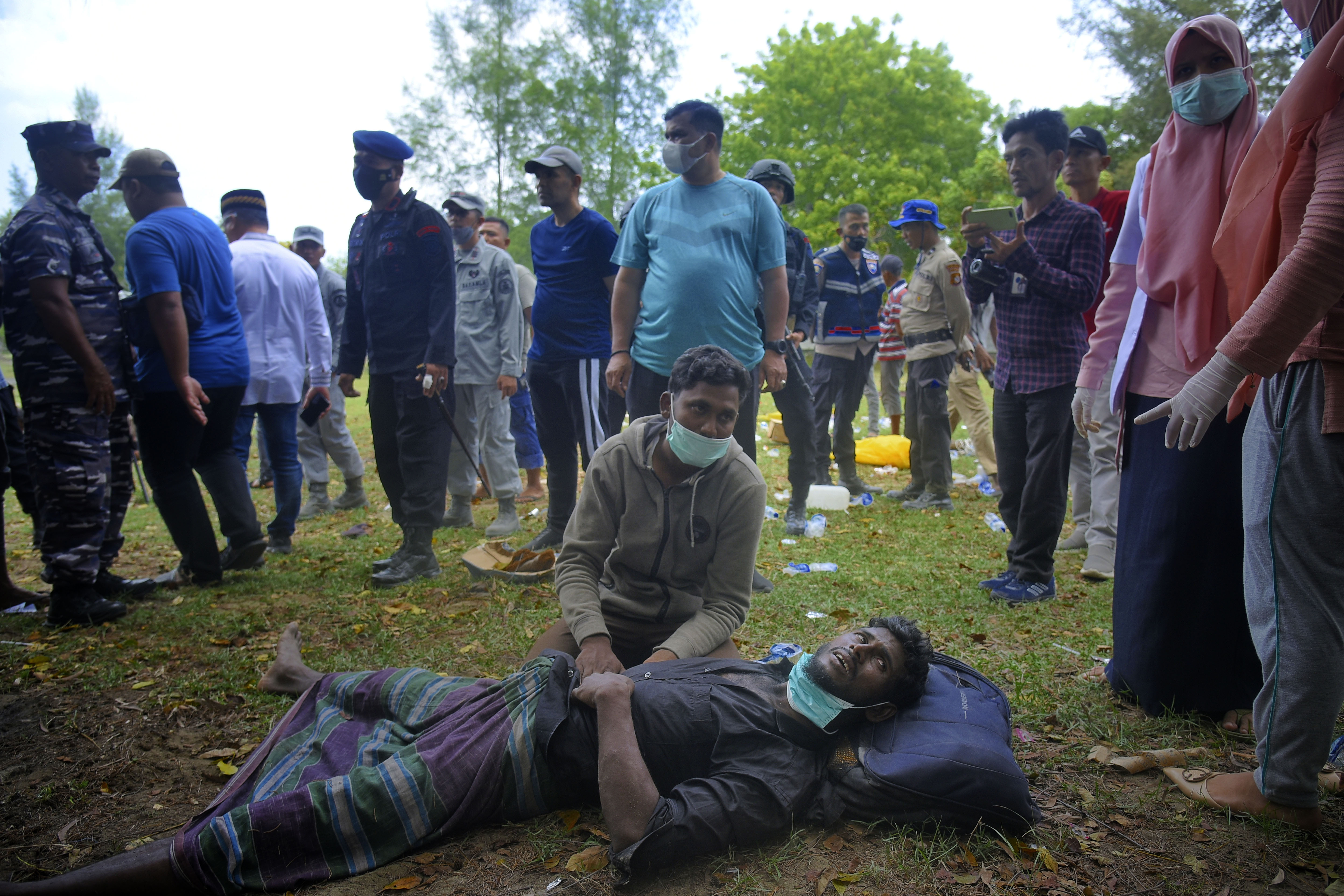 An ethnic Rohingya man lies on the ground as he waits for medical treatment