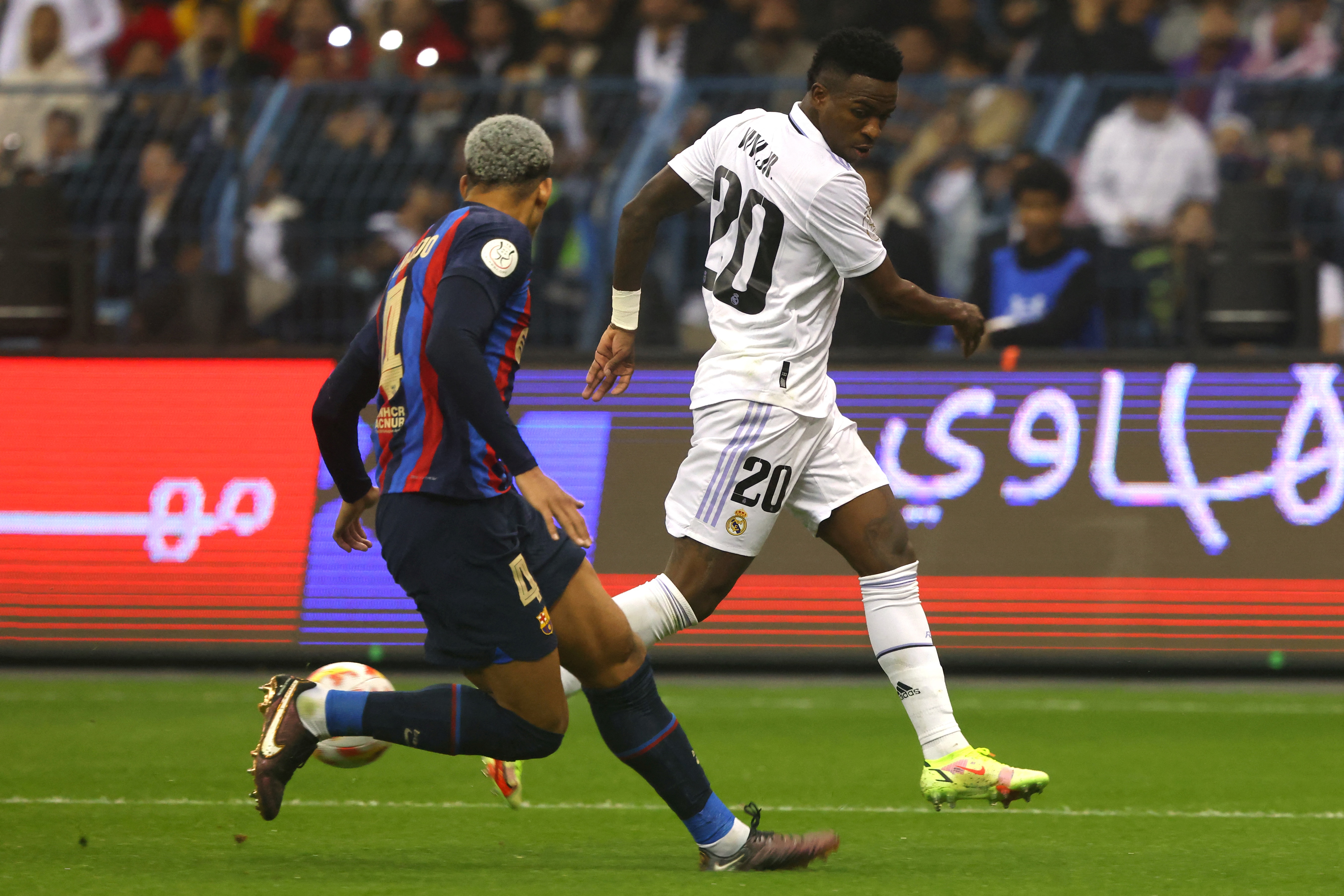 Real Madrid's Brazilian forward Vinicius Junior vies with Barcelona's Uruguayan defender Ronald Araujo (L) during the Spanish