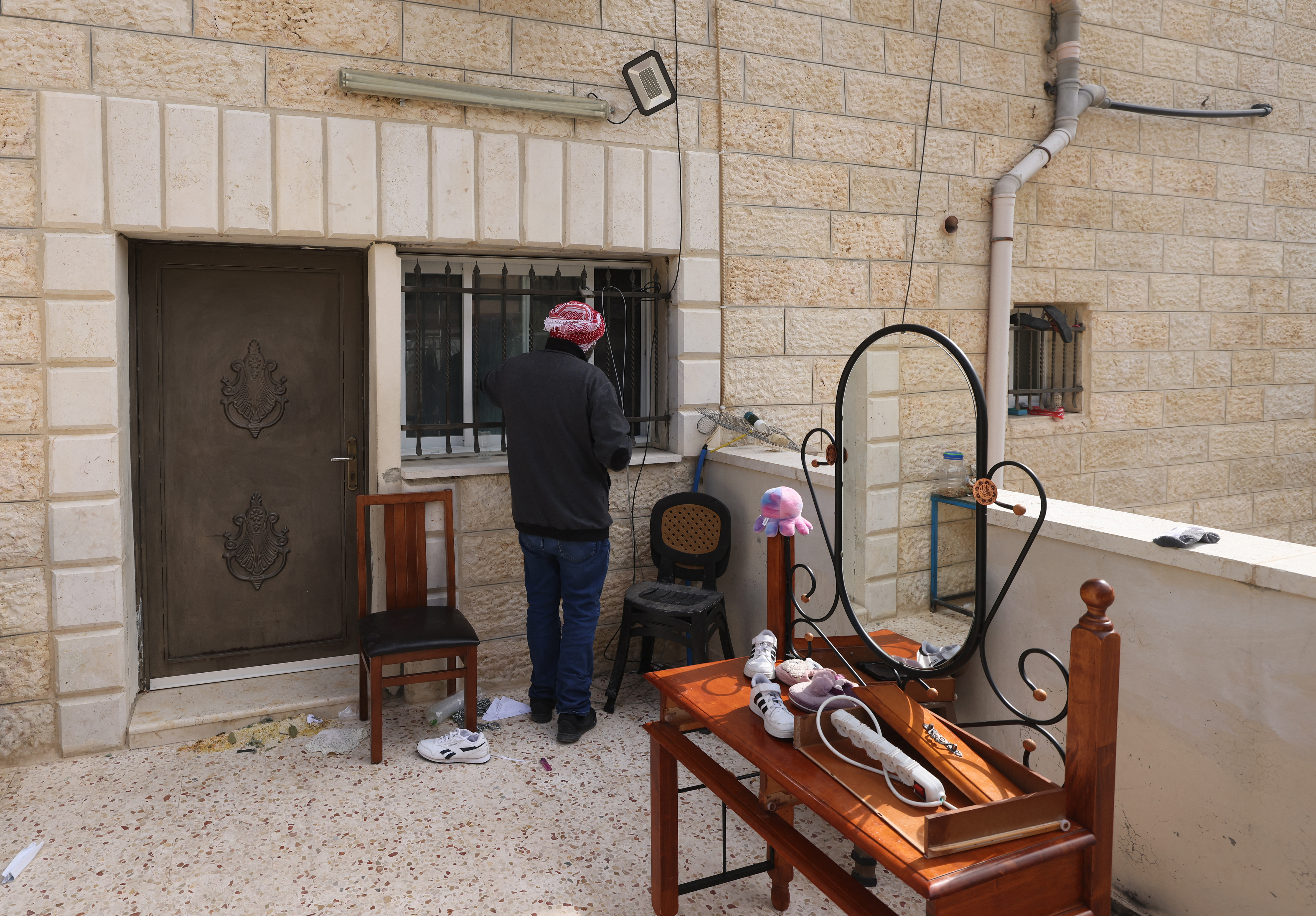A relative of a Palestinian gunman inspects the barricade put up by Israeli soldiers at the Alqam family home
