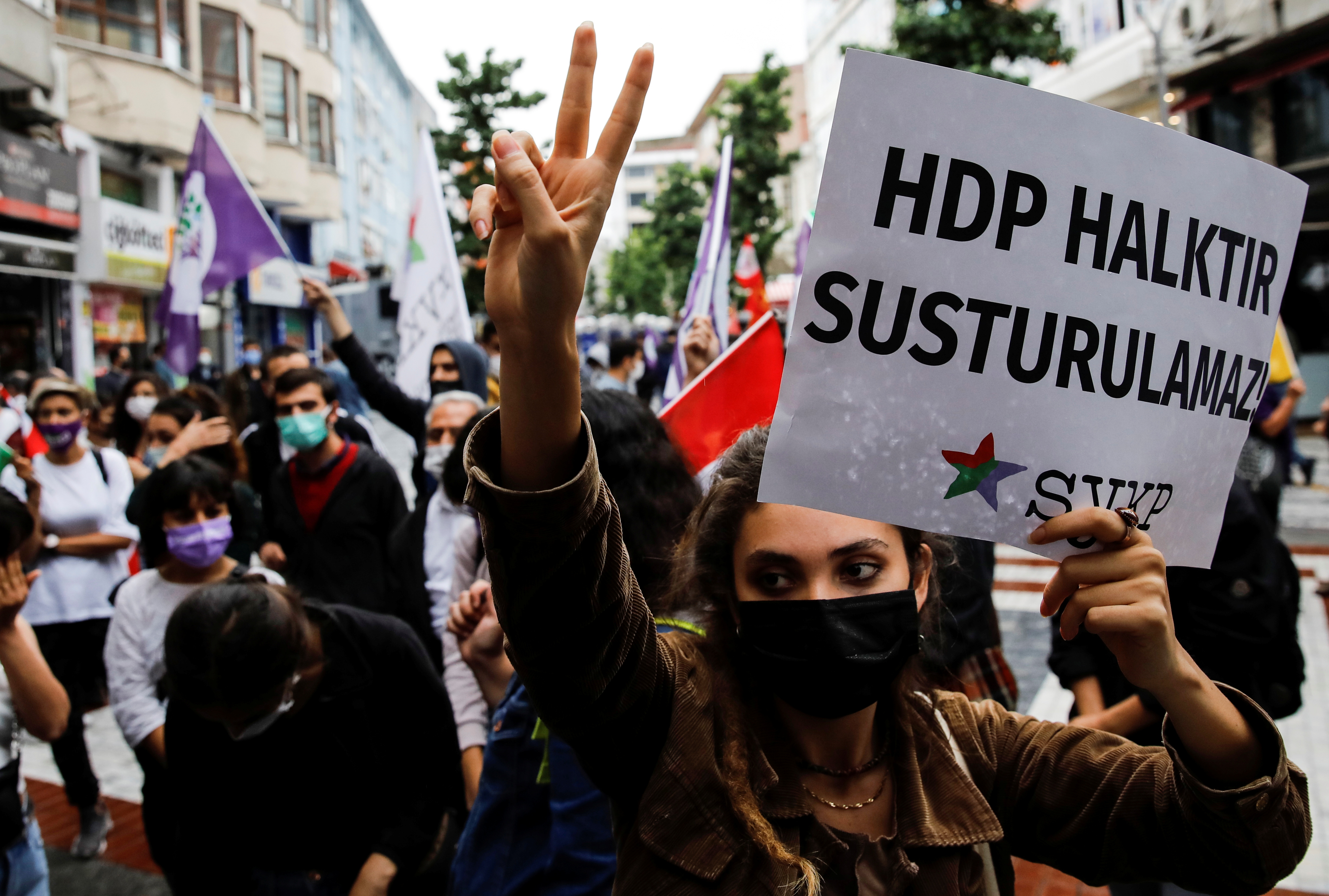 A demonstrator makes a v sign and holds a banner reads "HDP is people, they can't be silenced" during a protest in solidarity with pro-Kurdish Peoples' Democratic Party (HDP)
