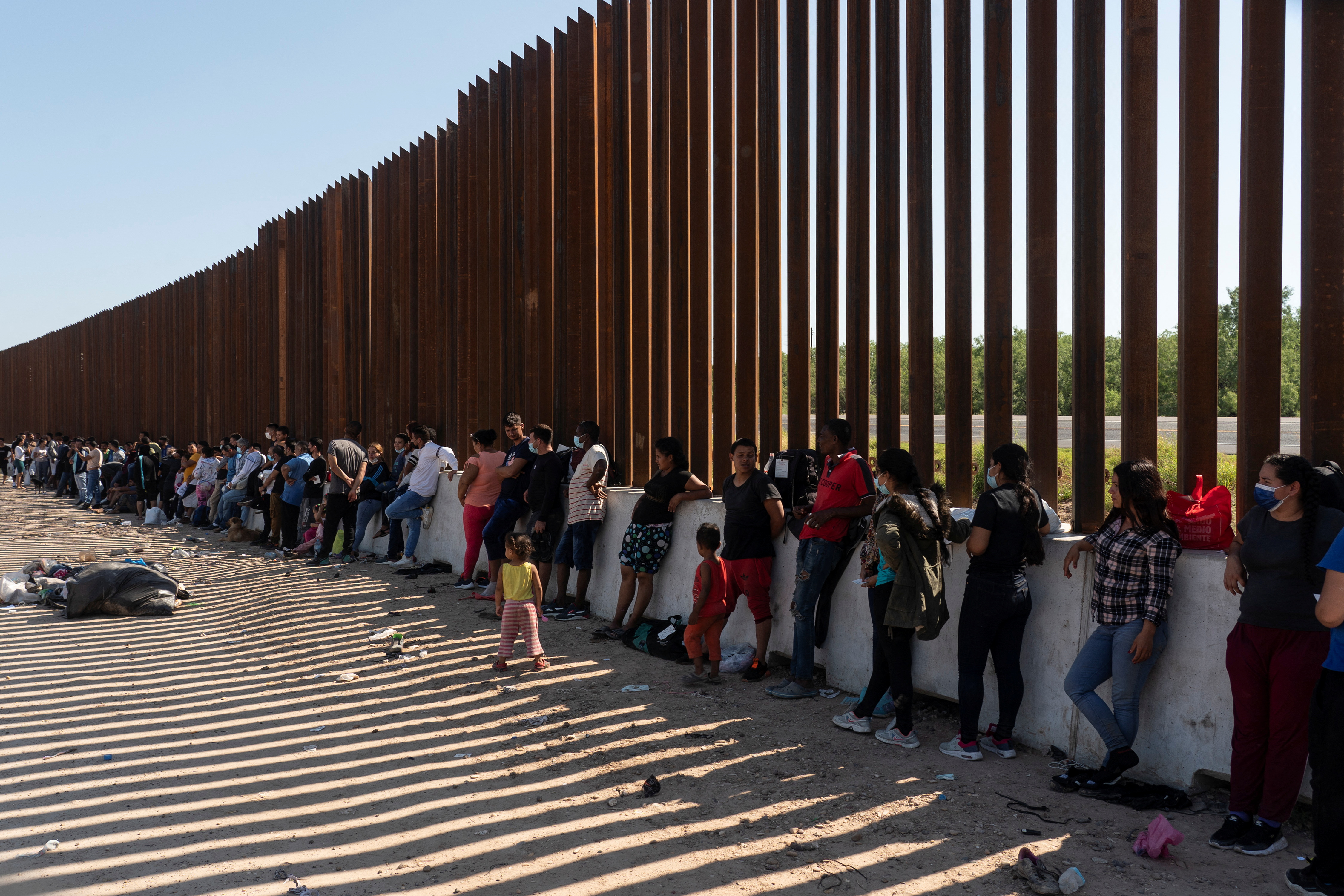 Asylum seeking migrants, mostly from Venezuela and Cuba, wait to be transported by U.S. Customs and Border Protection agents.