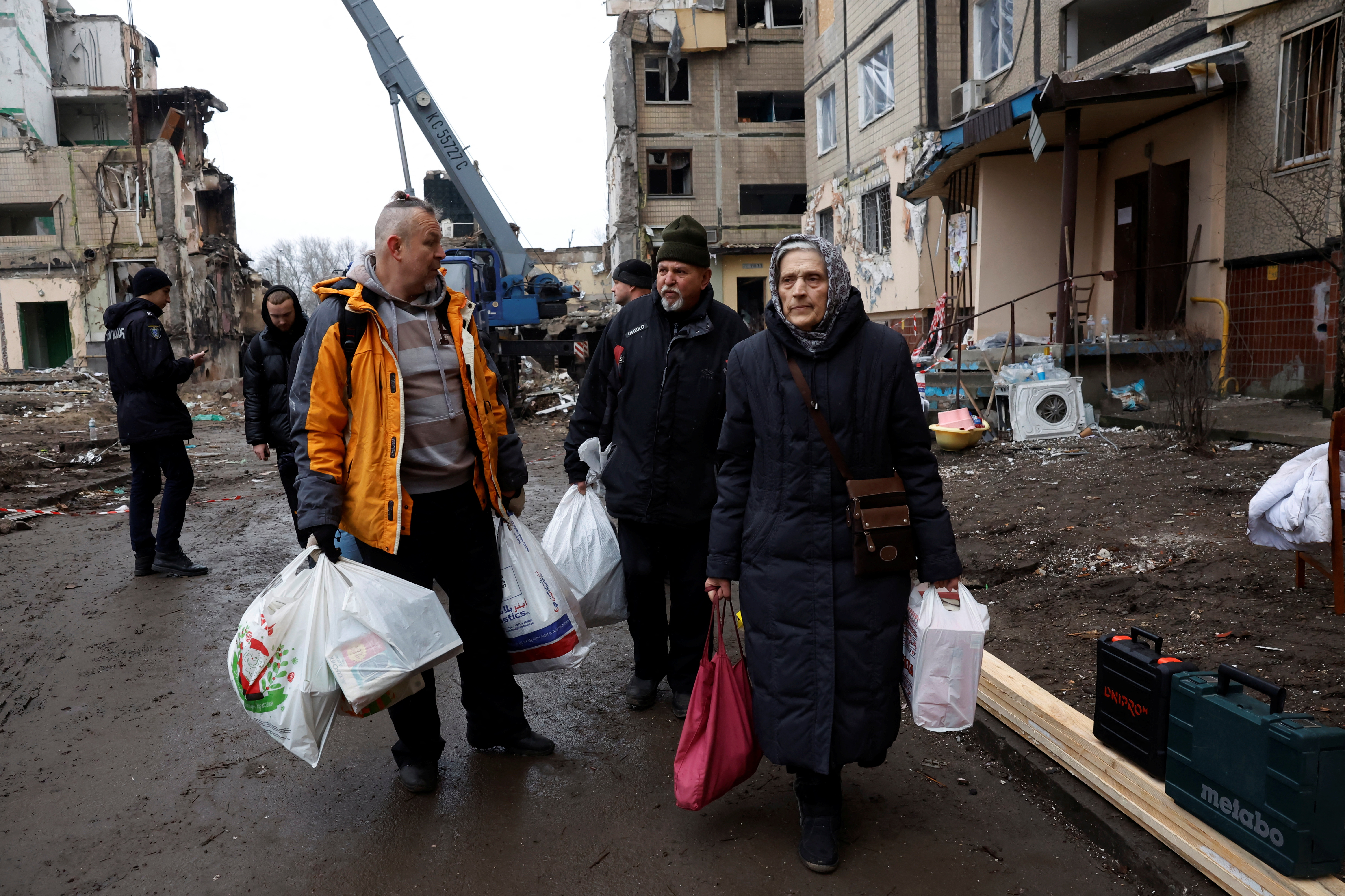 People stand among the wreckage of an apartment building damaged by Russian shelling in Ukraine's Dnipro