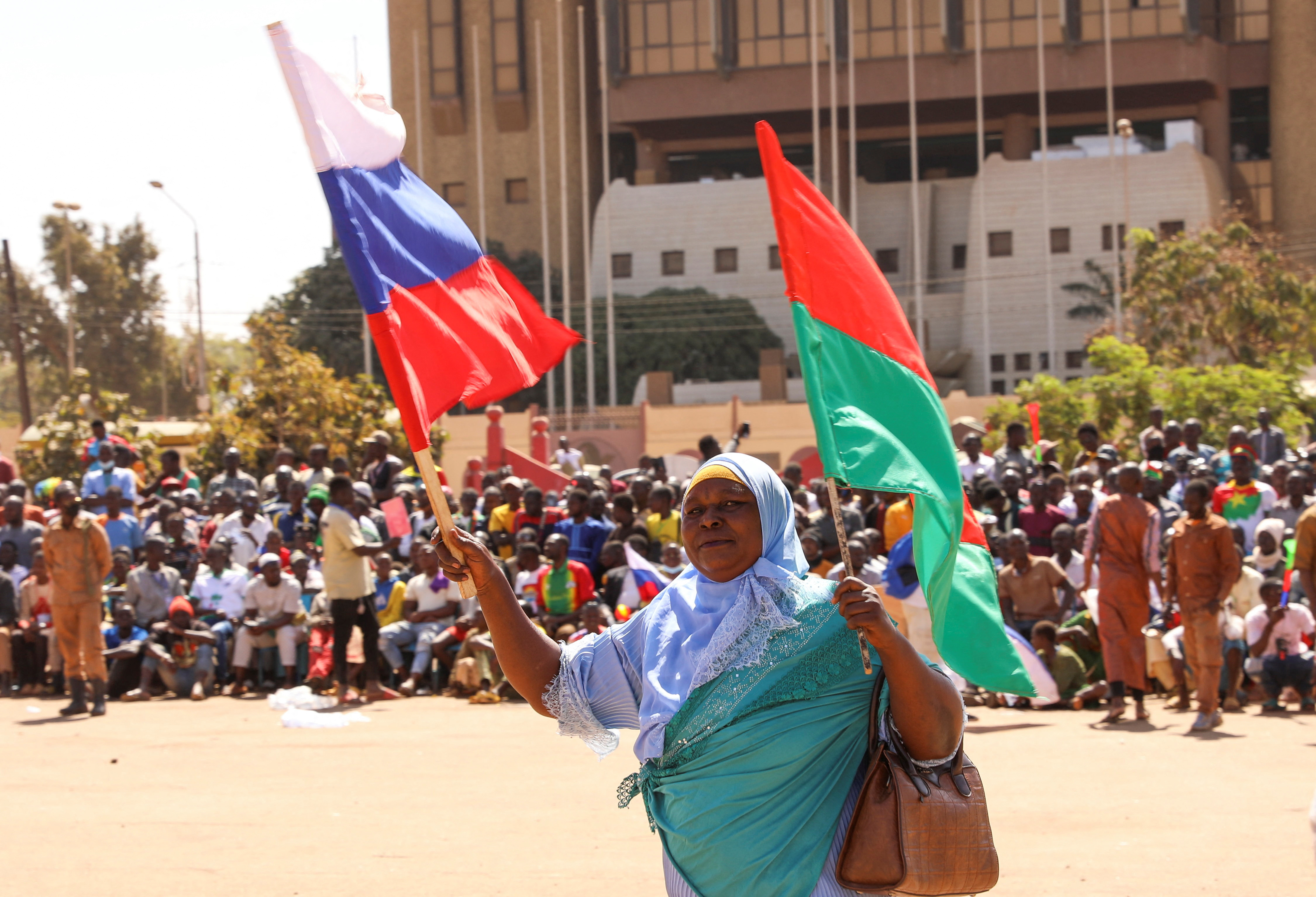A woman holds her national flag and the Russian flag as people gather to show their support for Burkina Faso’s new military leader Ibrahim Traore and demand the departure of the French ambassador at the Place de la Nation in Ouagadougou, Burkina Faso, January 20, 2023
