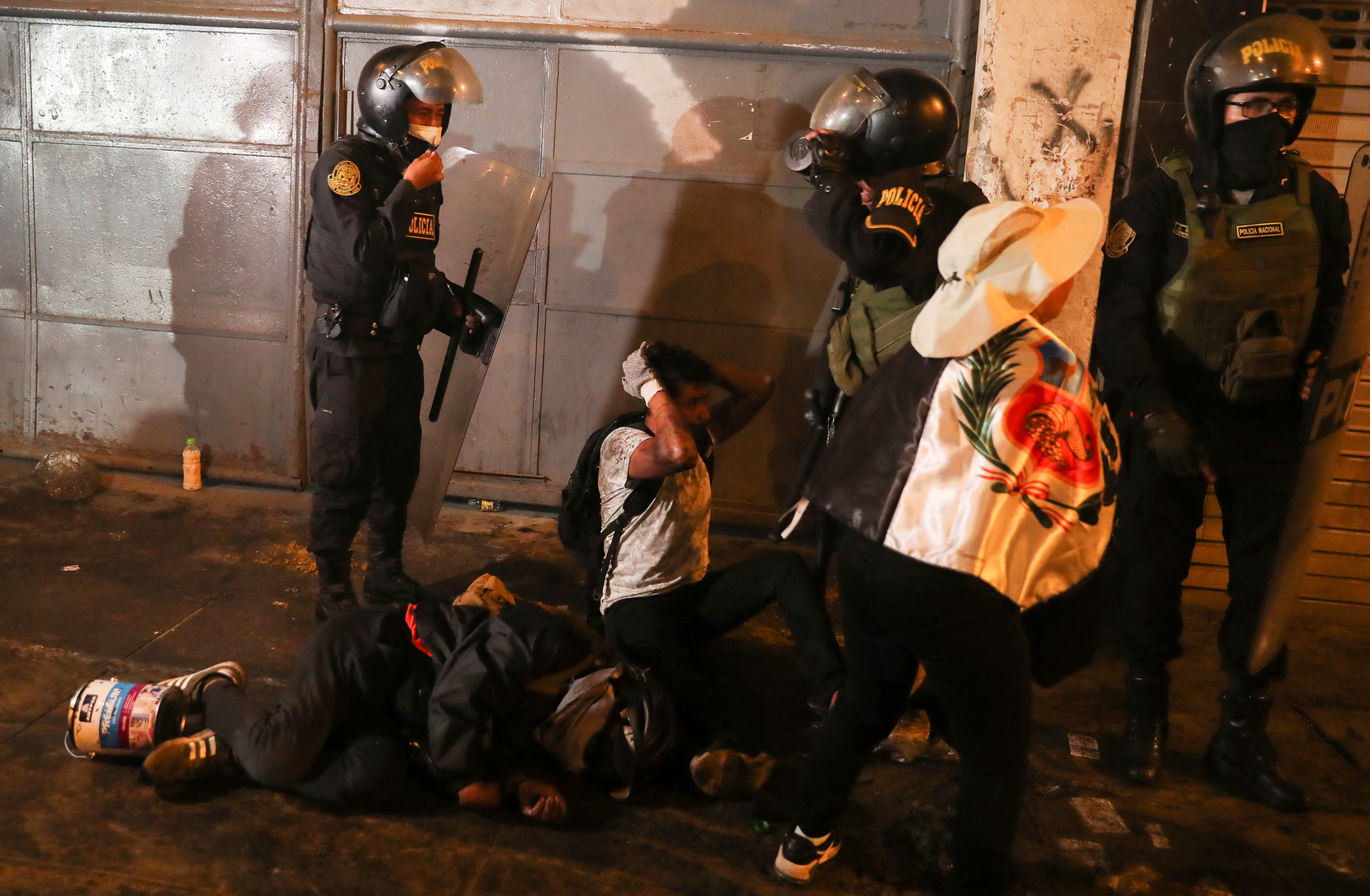 A protester on the ground takes cover as he is surrounded by riot police officers during the 'Take over Lima' march to demonstrate against Peru's President Dina Boluarte, following the ousting and arrest of former President Pedro Castillo, in Lima, Peru January 20, 2023.