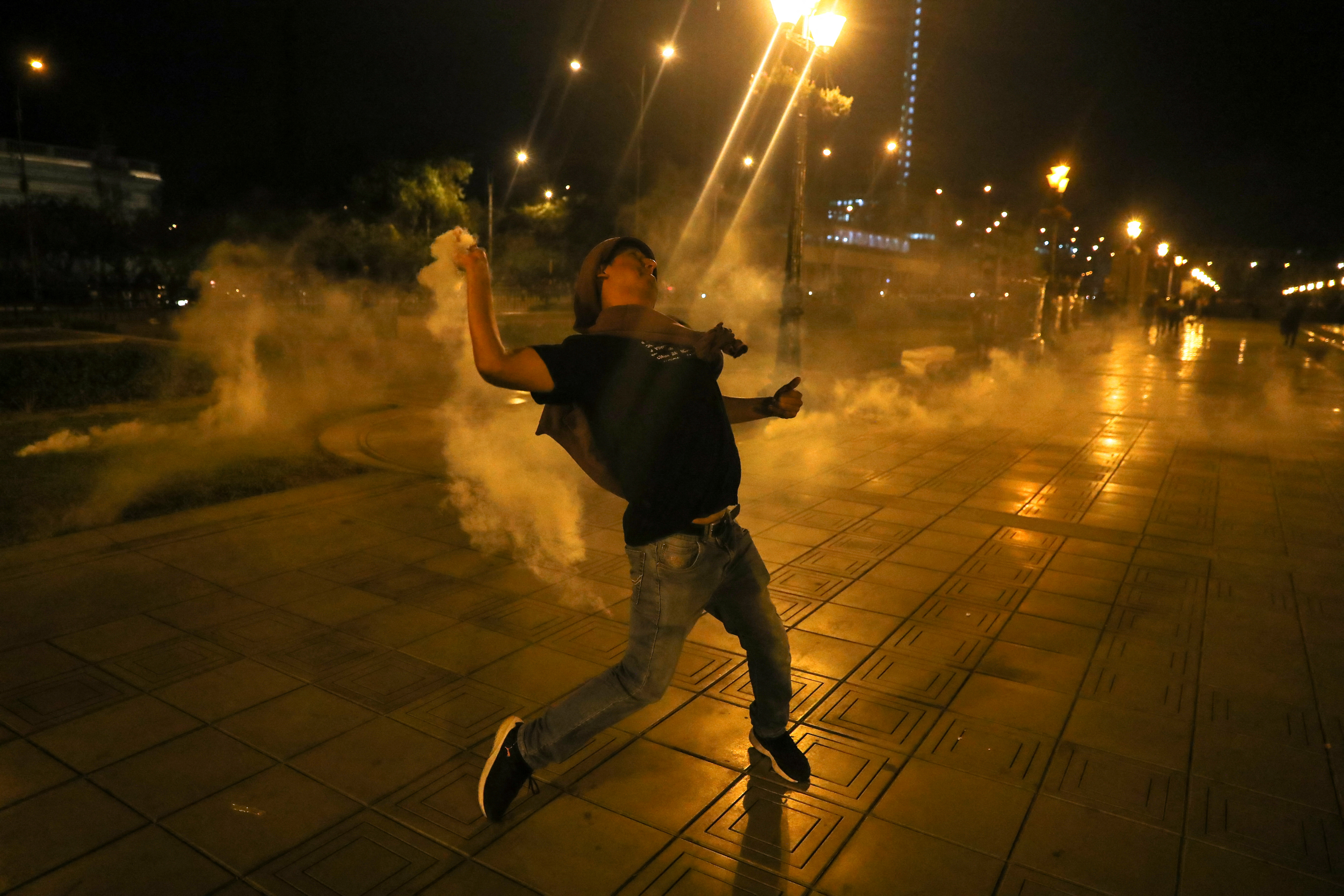 A protester throws a tear gas canister during the demonstrations in Lima, Peru