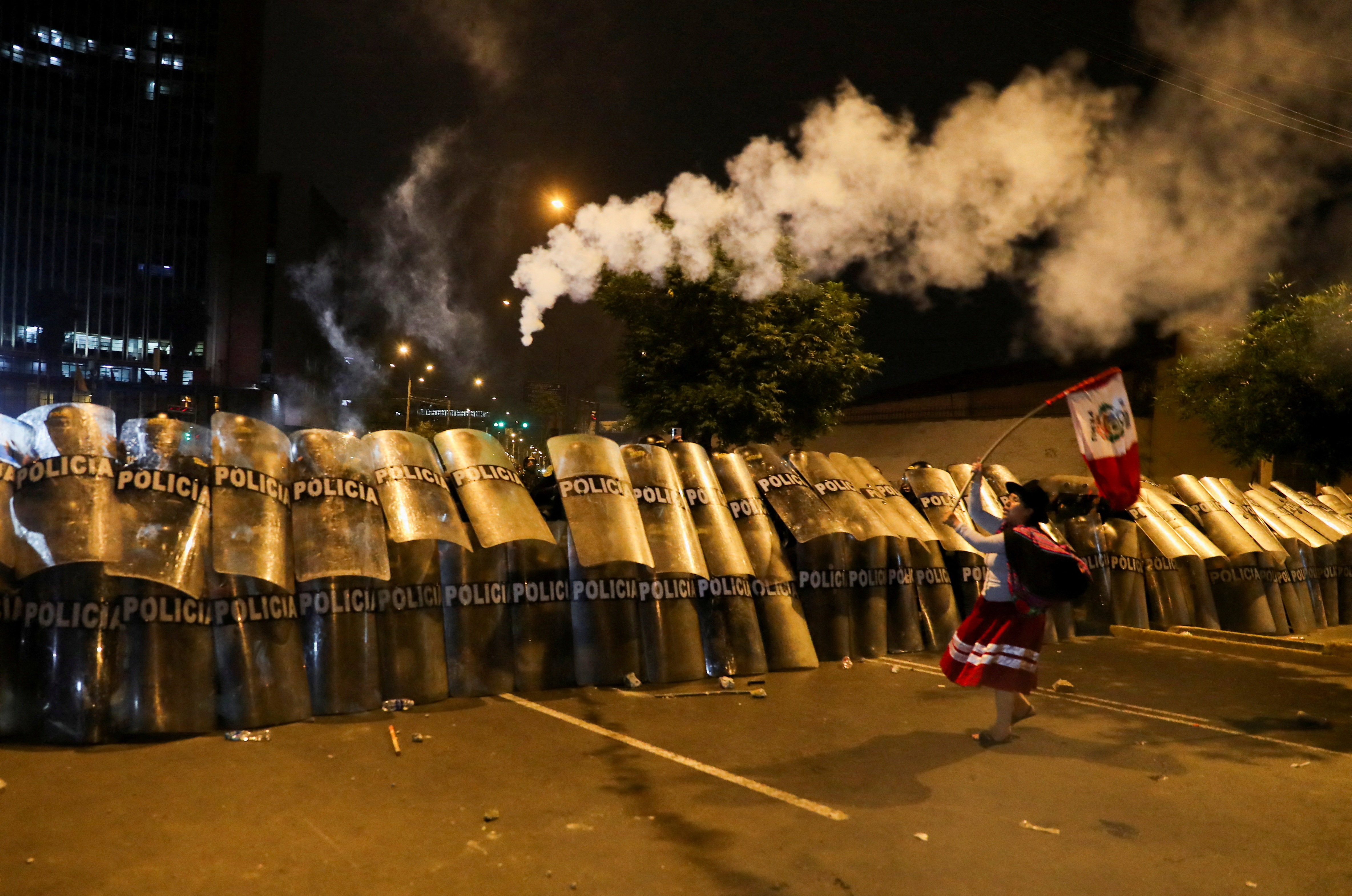A woman waves a Peruvian flag in front of riot police during the 'Take over Lima' march to demonstrate against Peru's President Dina Boluarte, following the ousting and arrest of former President Pedro Castillo, in Lima, Peru January 20, 2023.
