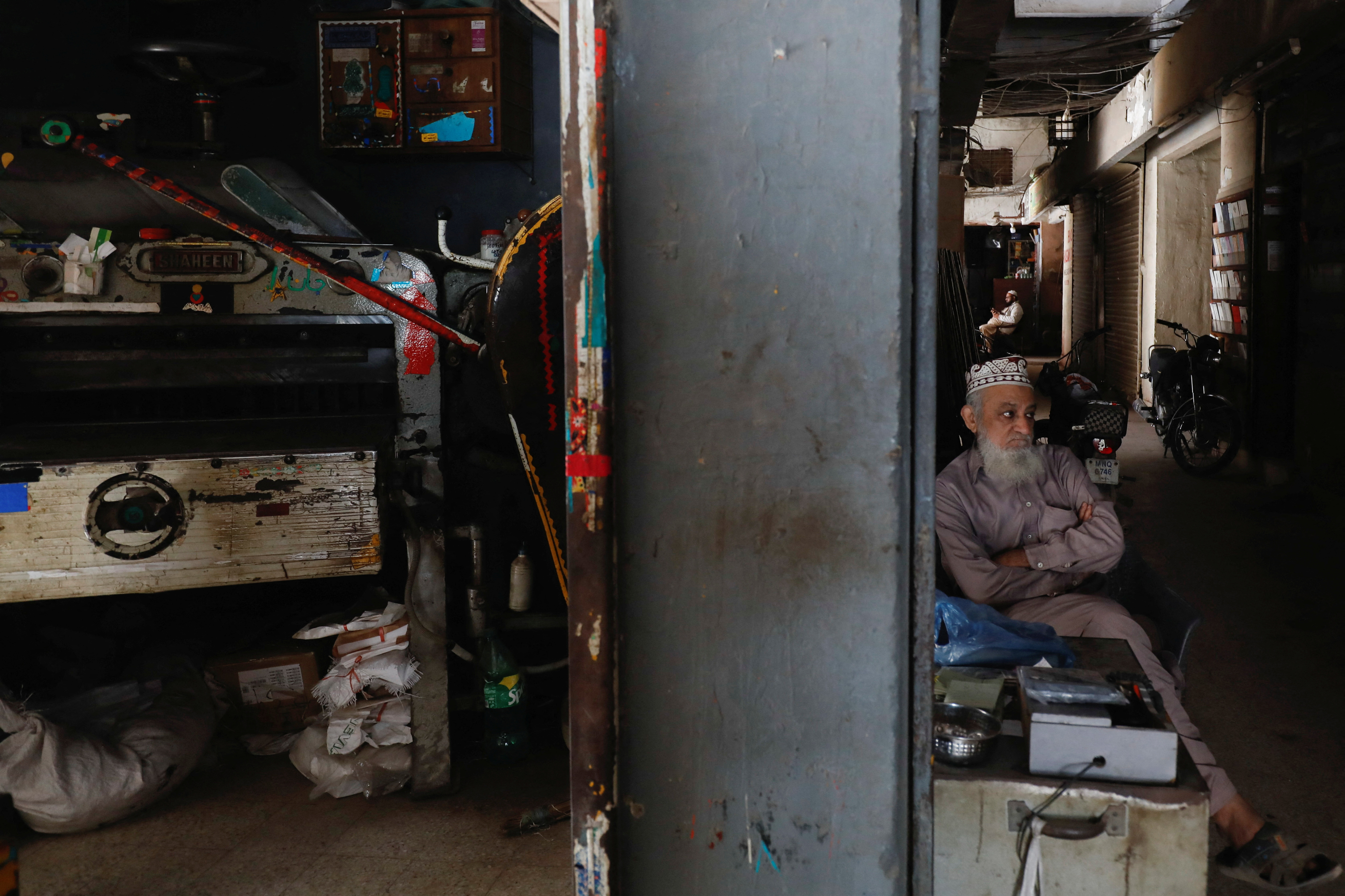A man sits outside his shop during a nationwide power breakdown in Karachi