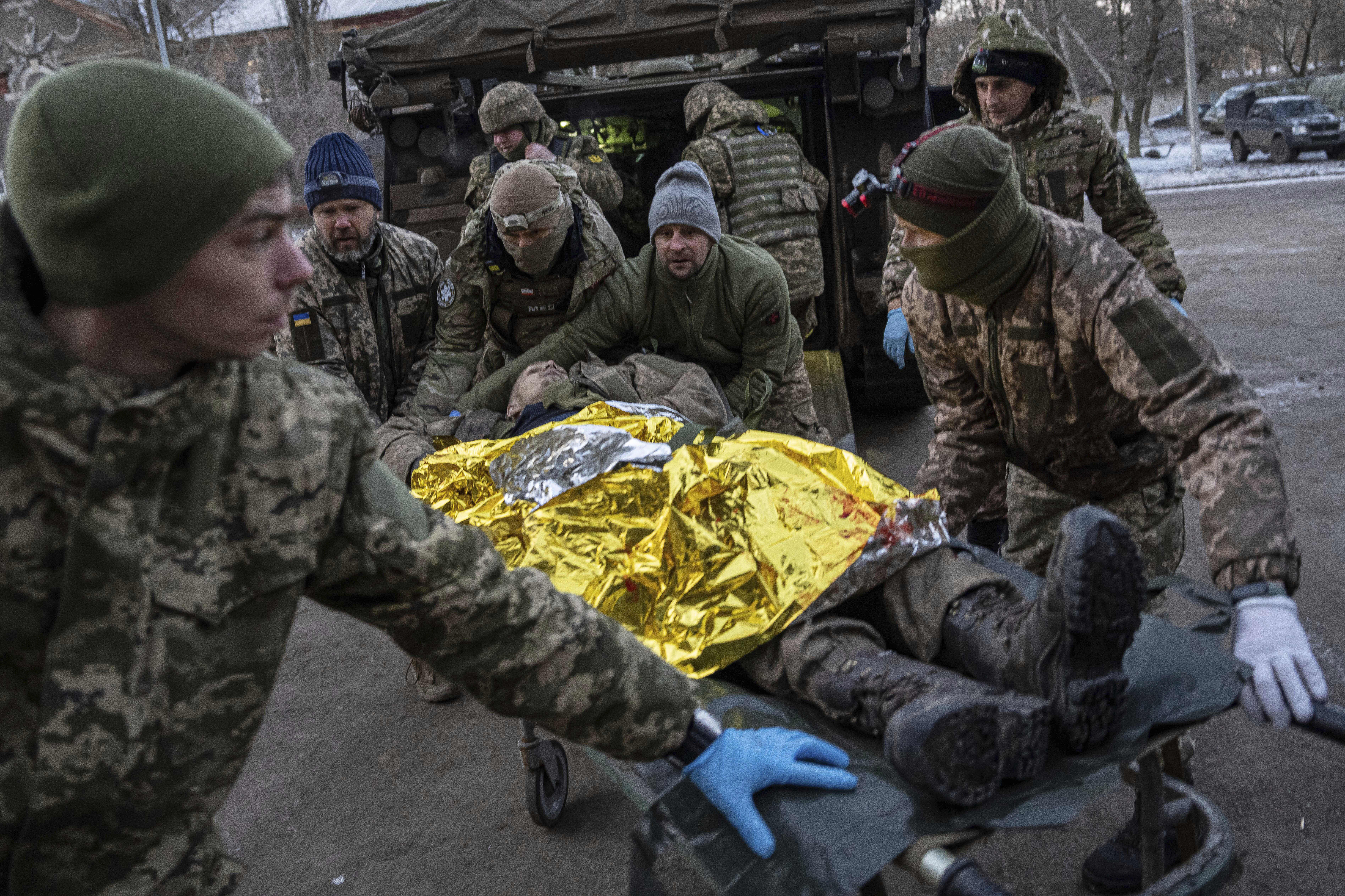 Ukrainian military medics carry an injured serviceman evacuated from the battlefield into a hospital in Donetsk region