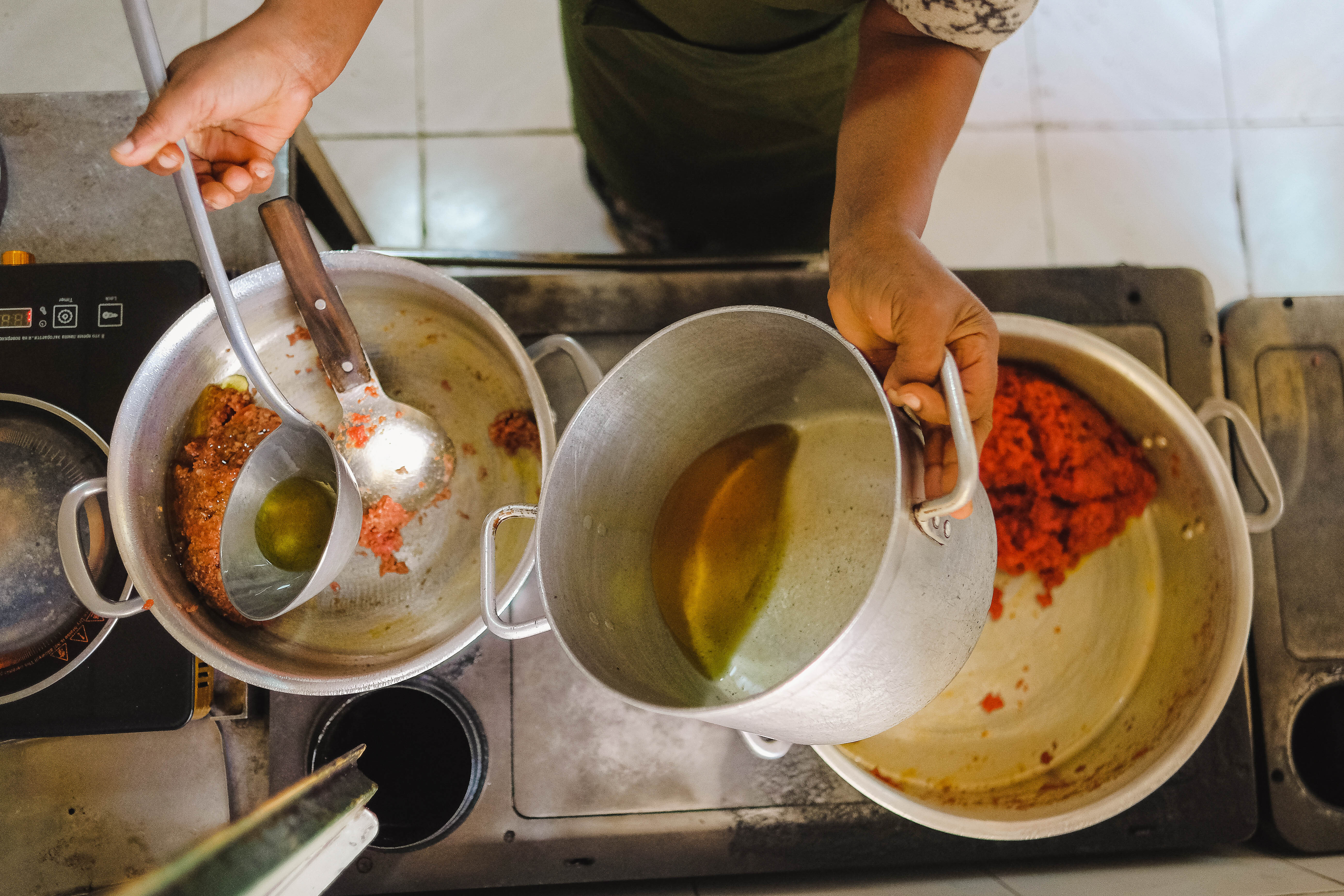 A ovverhead shot of a cook adding niter kibe to a pot of kitfo