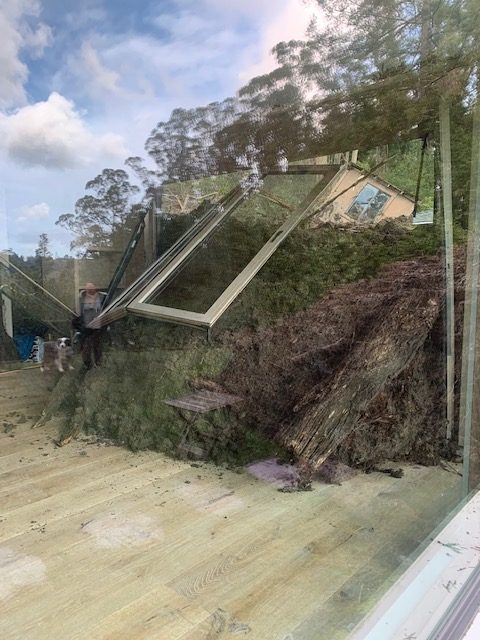 Seen through a window, a mudslide crashes through a wall