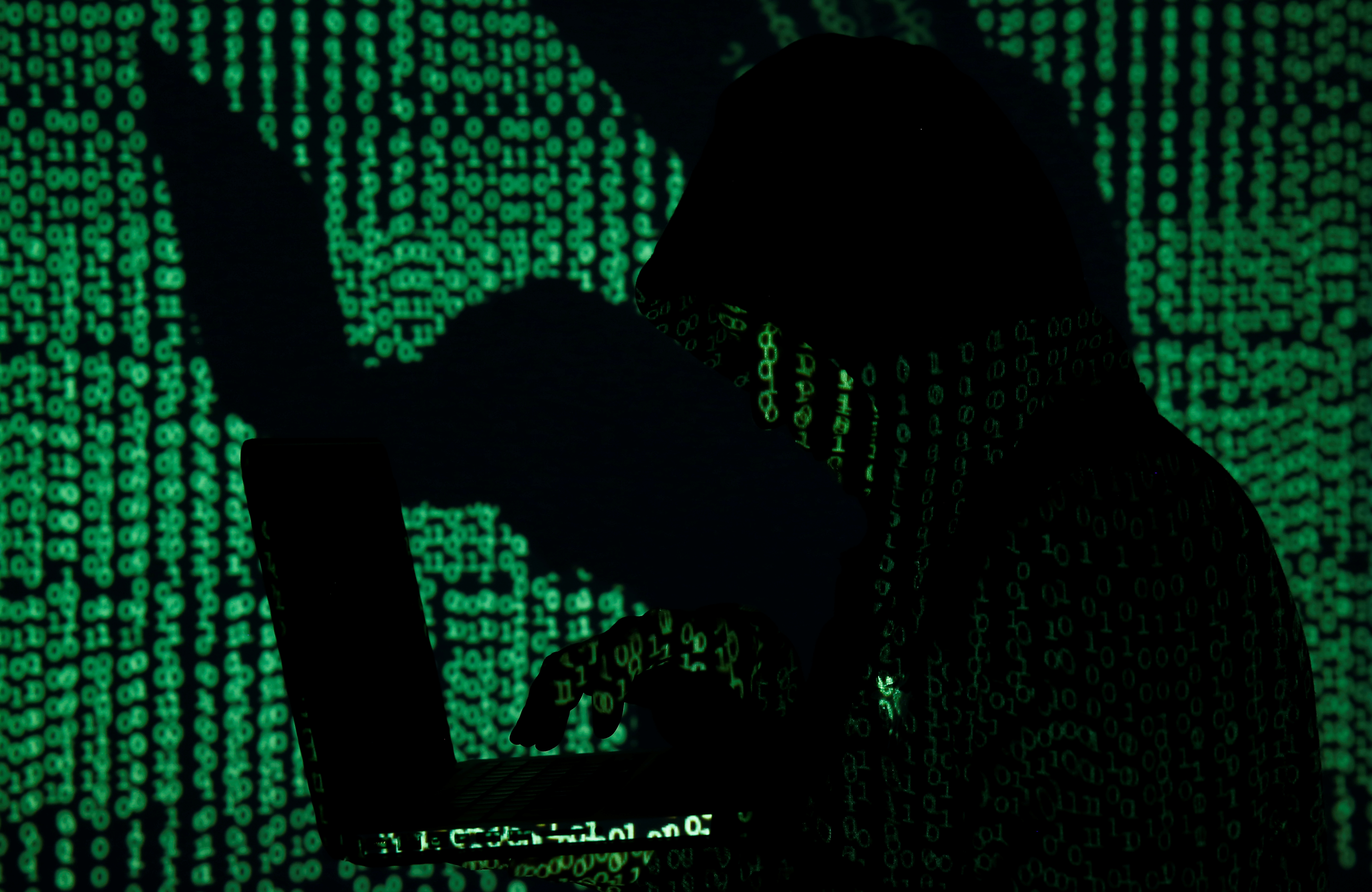 A man holds a laptop computer as cyber code is projected on him in this illustration picture taken on May 13, 2017. Capitalizing on spying tools believed to have been developed by the U.S. National Security Agency, hackers staged a cyber assault with a self-spreading malware that has infected tens of thousands of computers in nearly 100 countries.