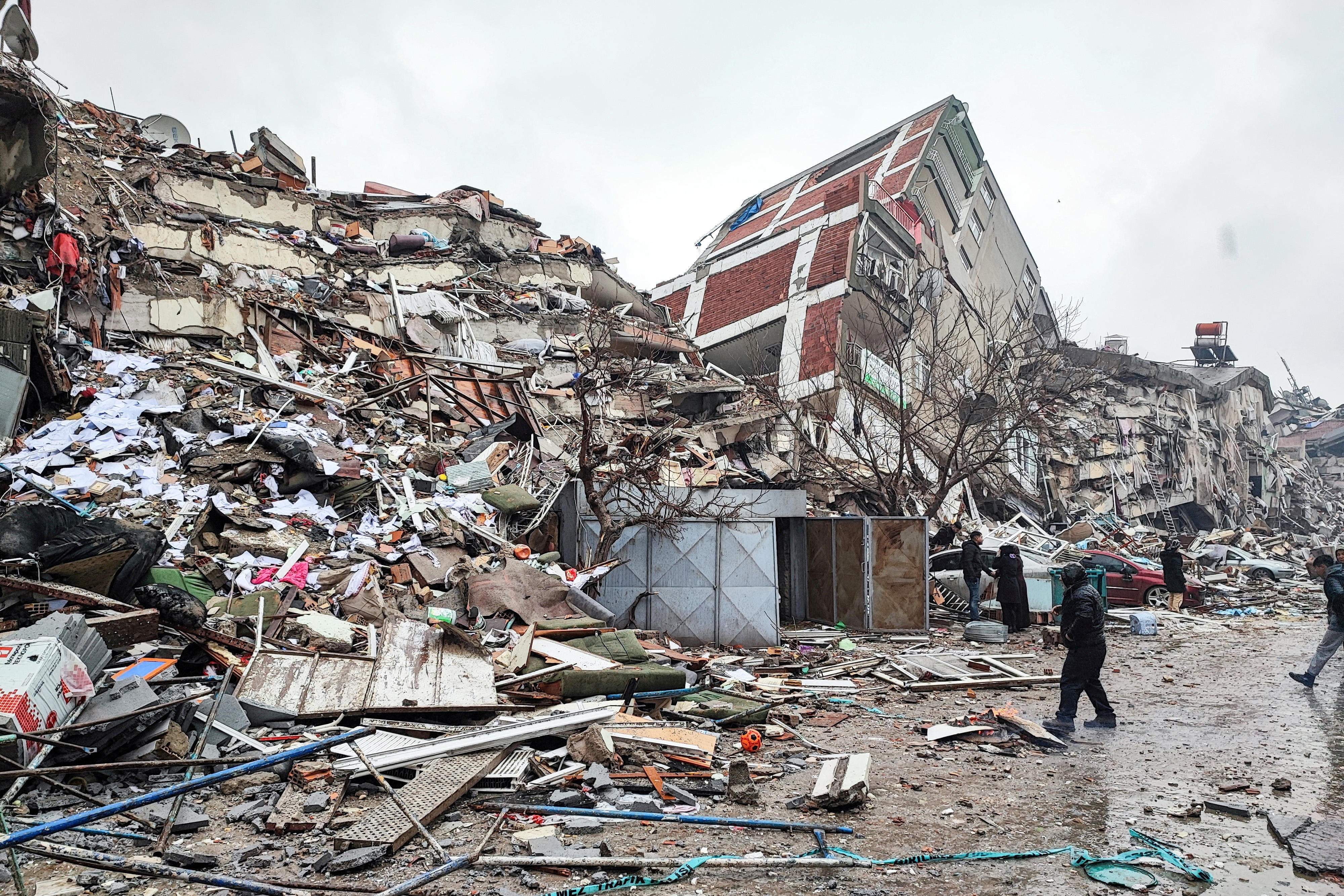People stand in front of collapsed buildings following an earthquake in Kahramanmaras, Turkey.