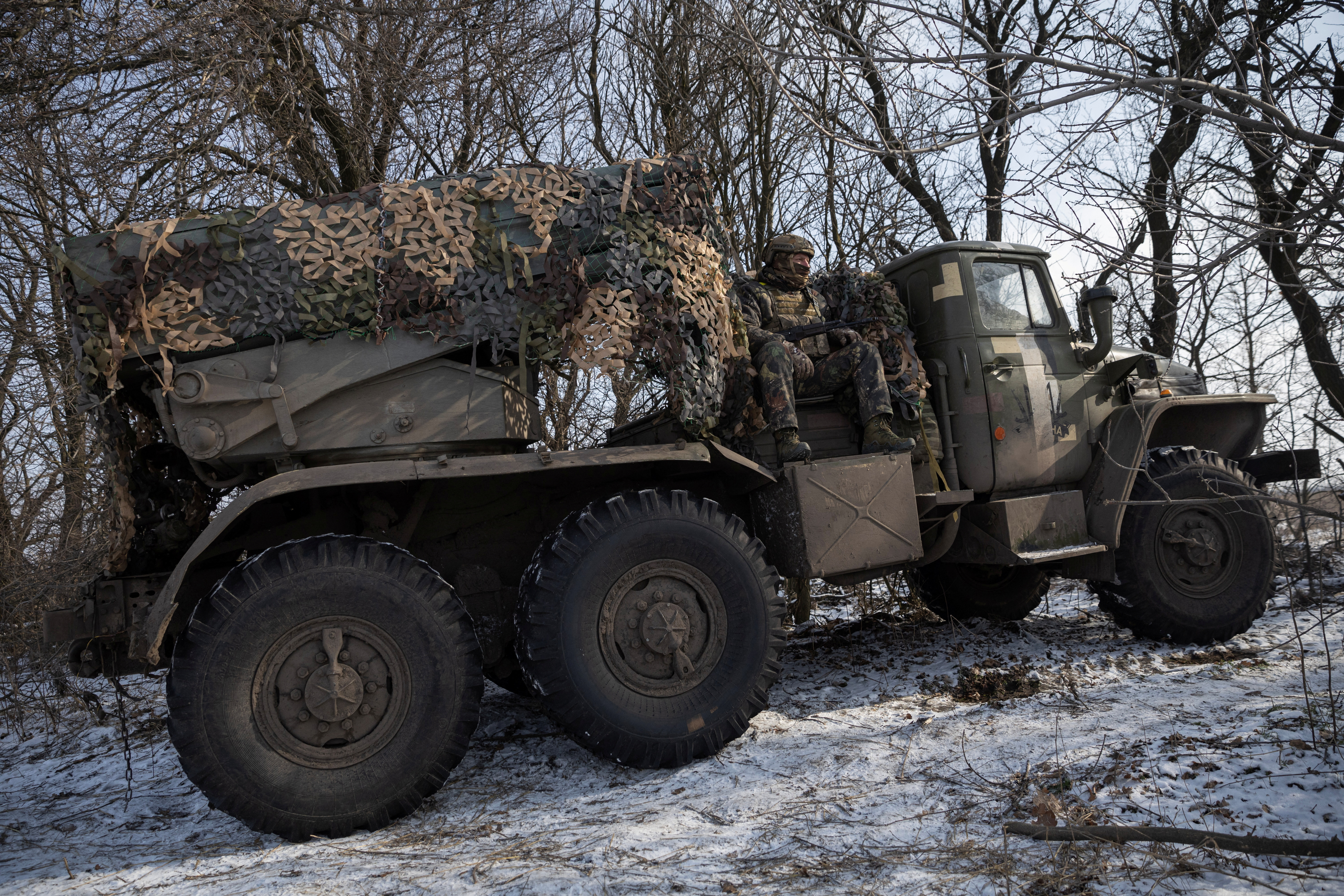 Ukrainian servicemen ride in a BM-21 Grad multiple rocket launch system as they prepare to fire it towards Russian positions on the front line near the eastern town of Maryinka