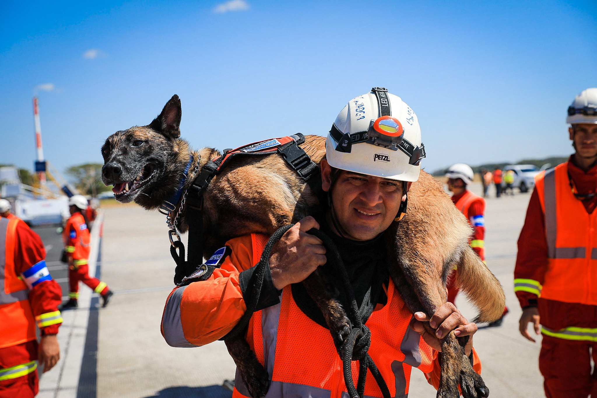 A member of El Salvador's Urban Search And Rescue Team (USAR) carry a rescue dog