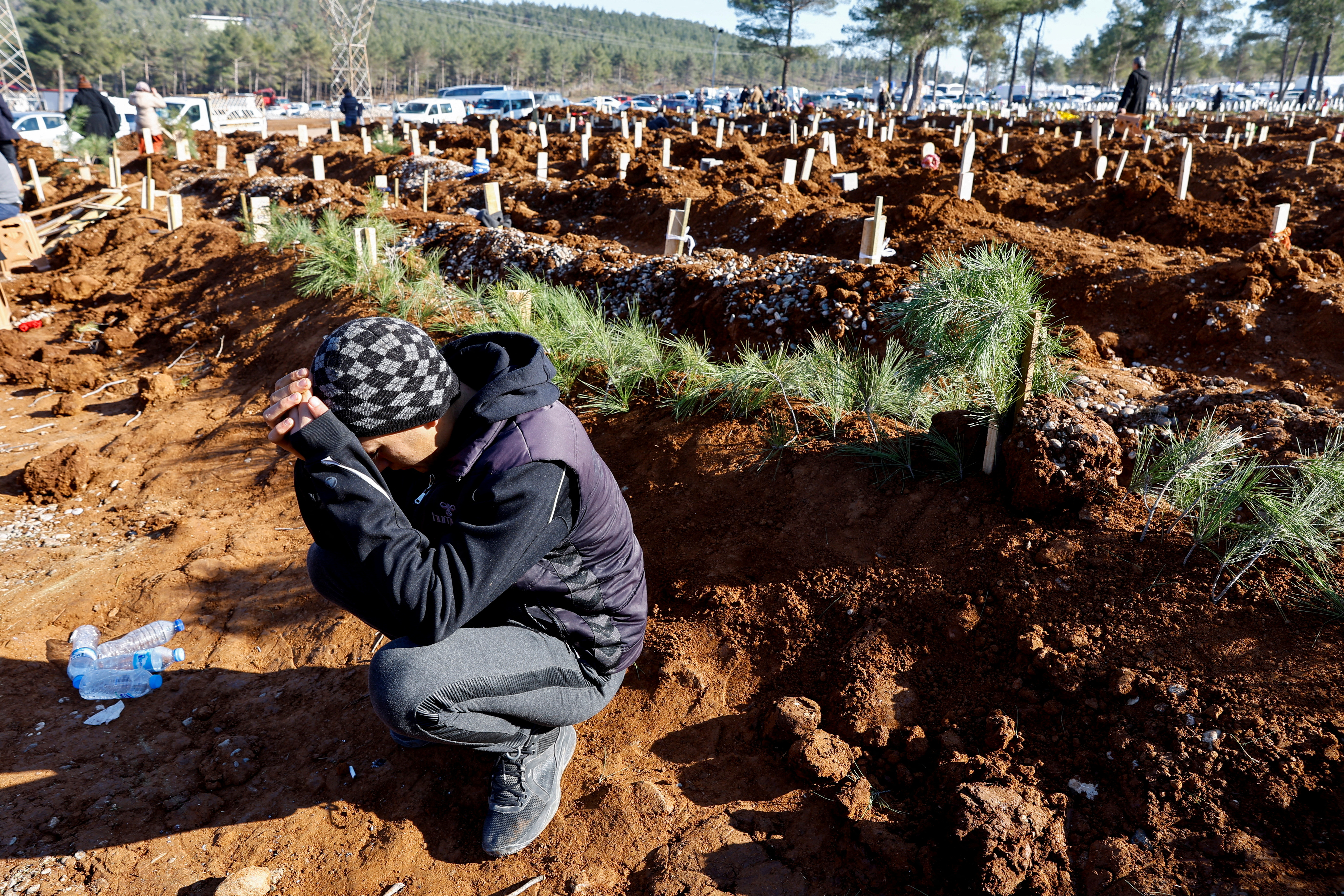 A man reacts next to the graves of victims of the deadly earthquake, in a cemetery in Kahramanmaras, Turkey