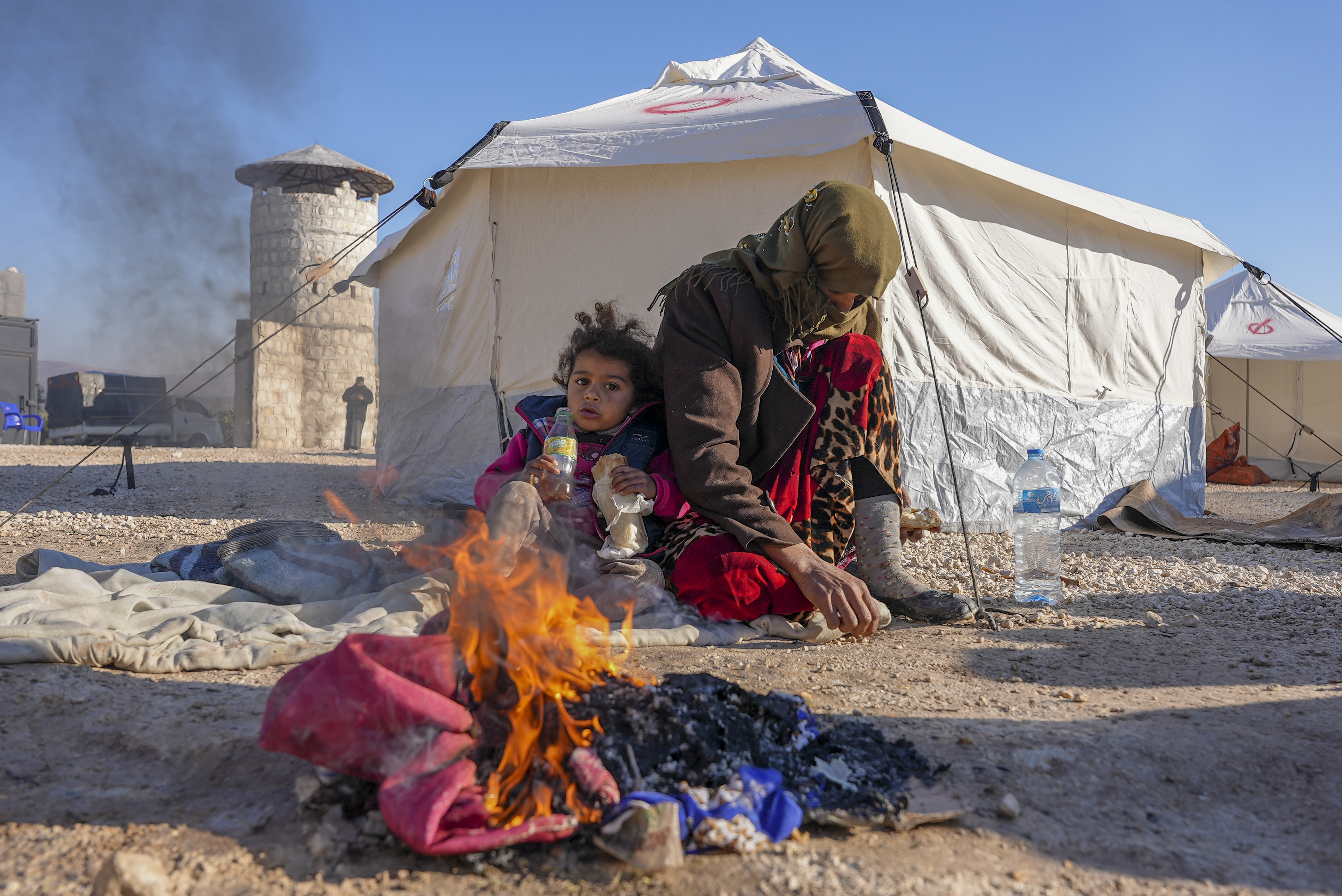 Syrians warm up by a fire at a makeshift shelter for people who were left homeless near the rebel-held town of Jandaris [Rami al Sayed/AFP)