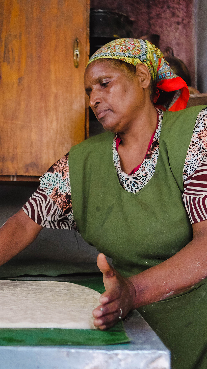 Menteha Hussain flattens a layer of kocho dough on false banana leaves