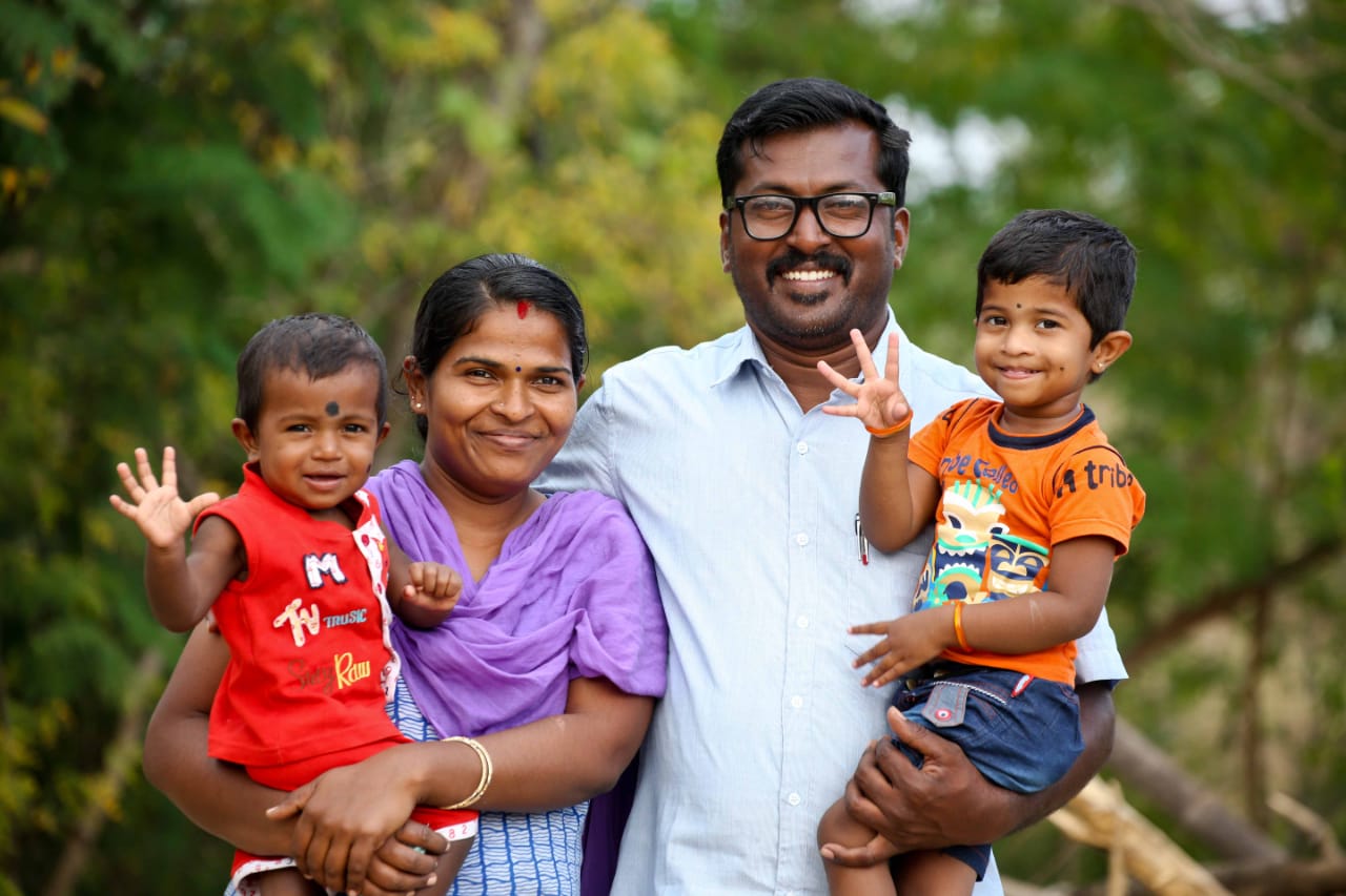 A photo of a family of four with a woman and a man and each one holding a child in their arms.