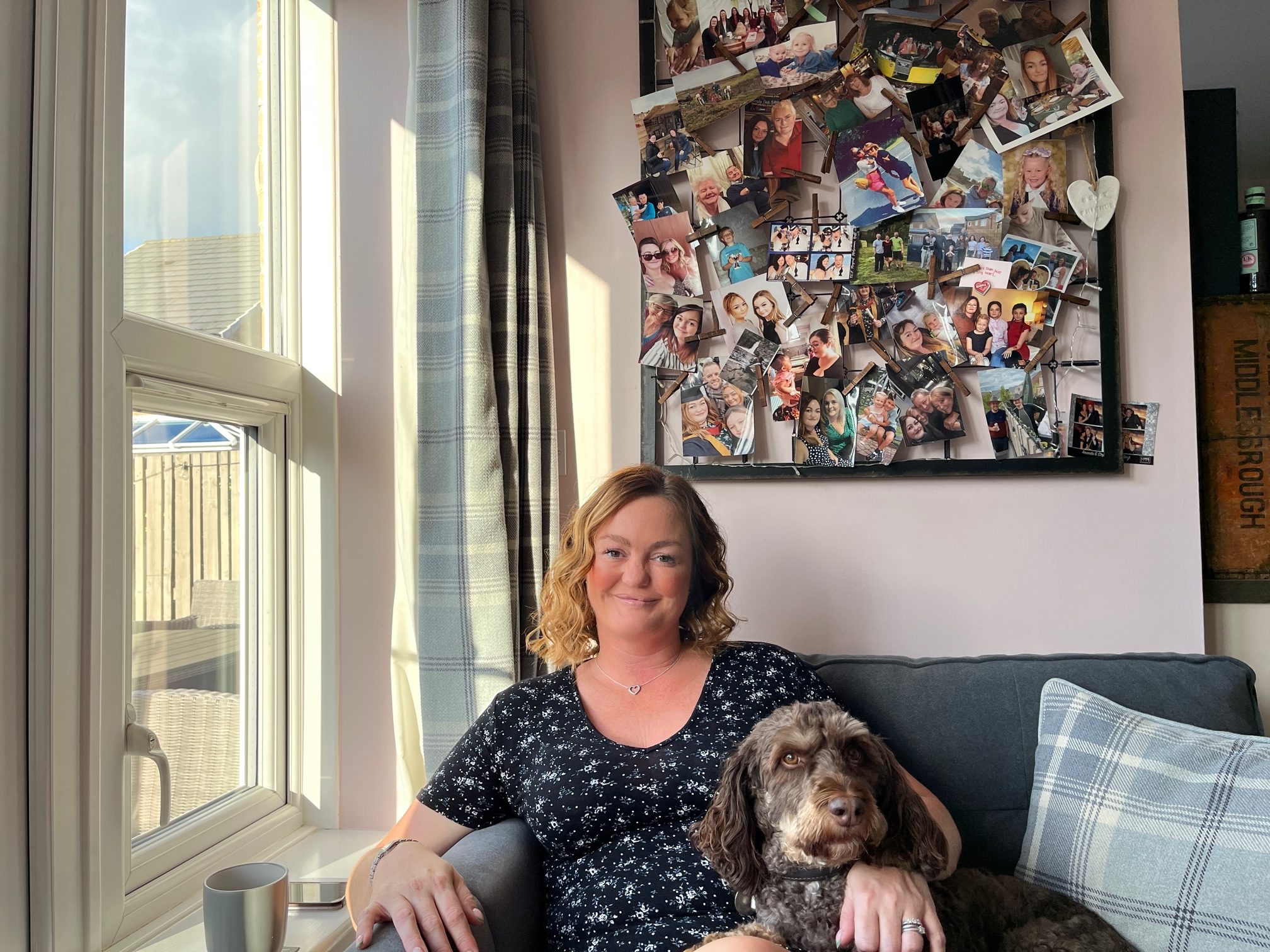 A woman sits beside a window with her dog