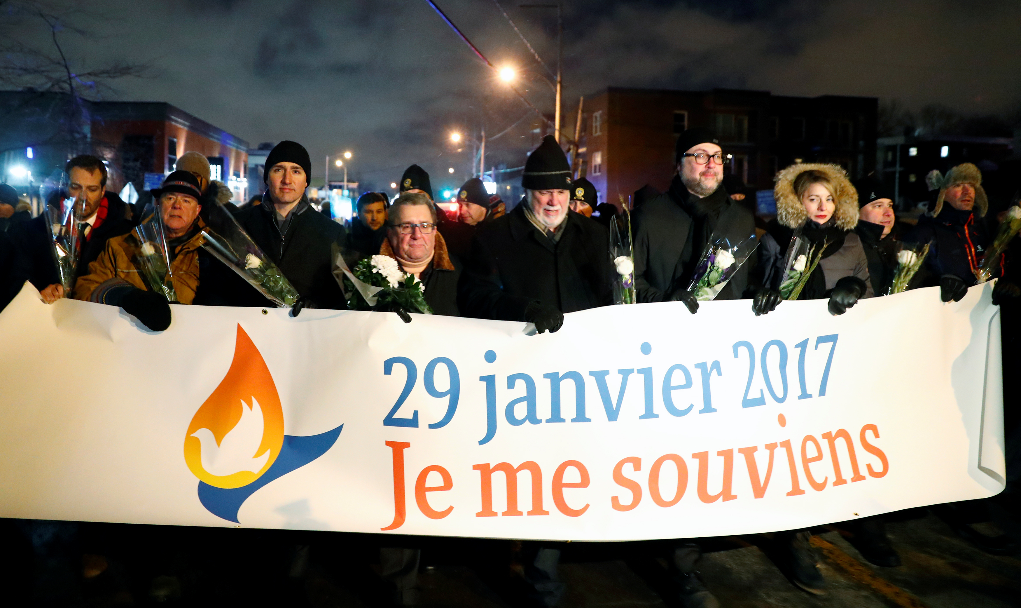 Canada's Prime Minister Justin Trudeau and Quebec's Premier Philippe Couillard hold a banner during a march near the Centre Culturel Islamique de in Quebec City, January 29, 2018.