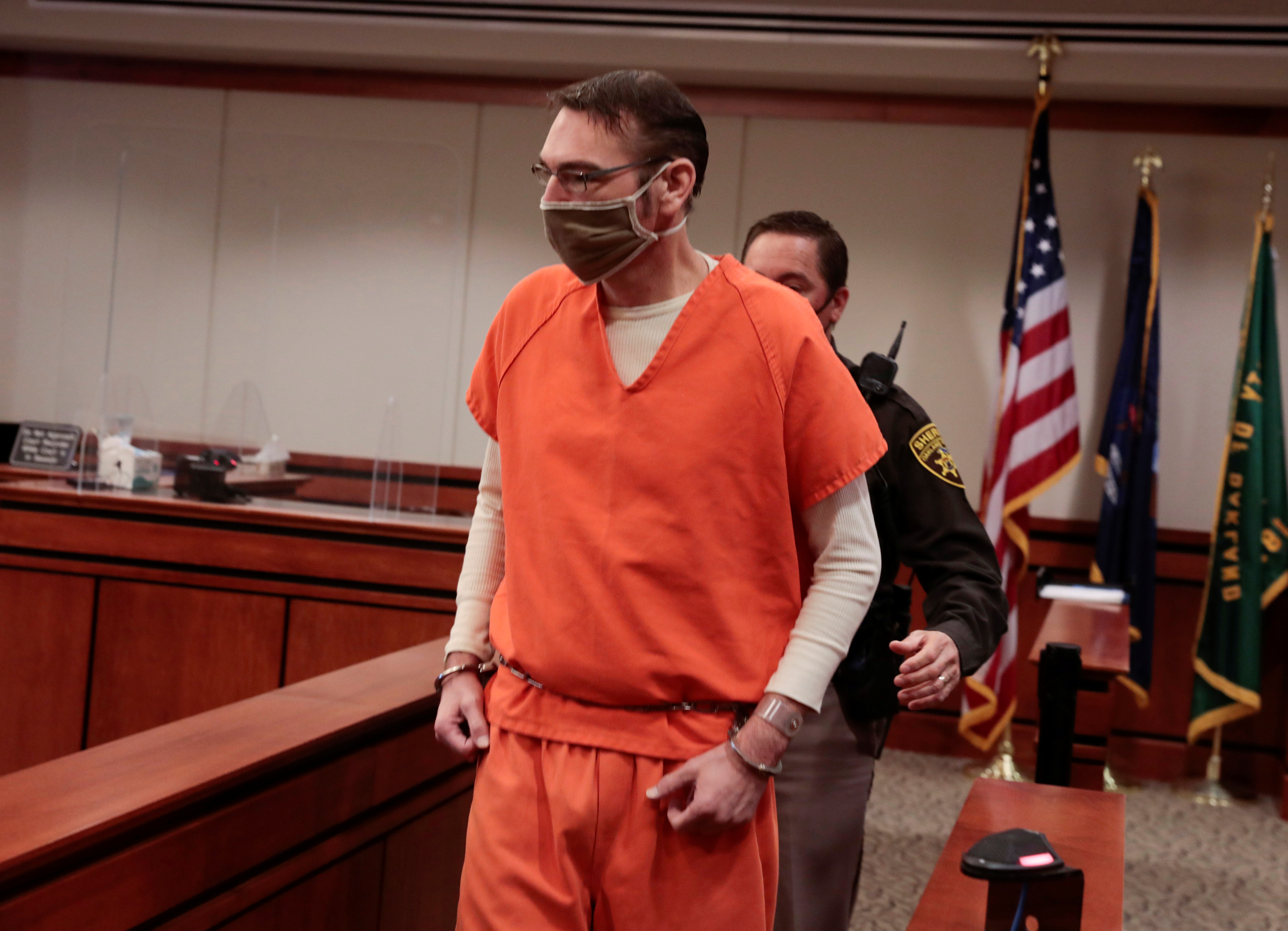 A man in an orange jump suit traverses a court