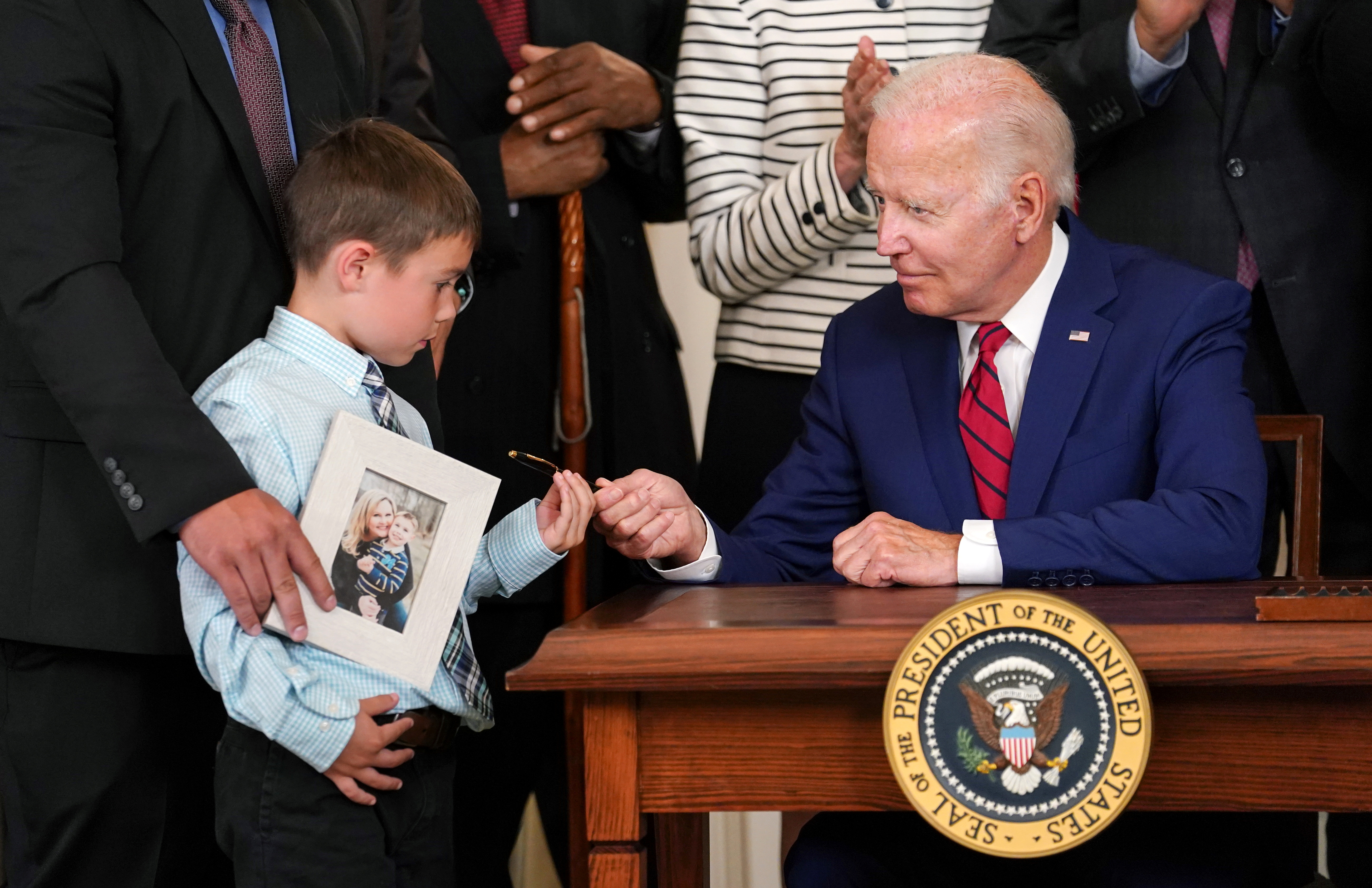 A young boy receives a pen from US President Joe Biden