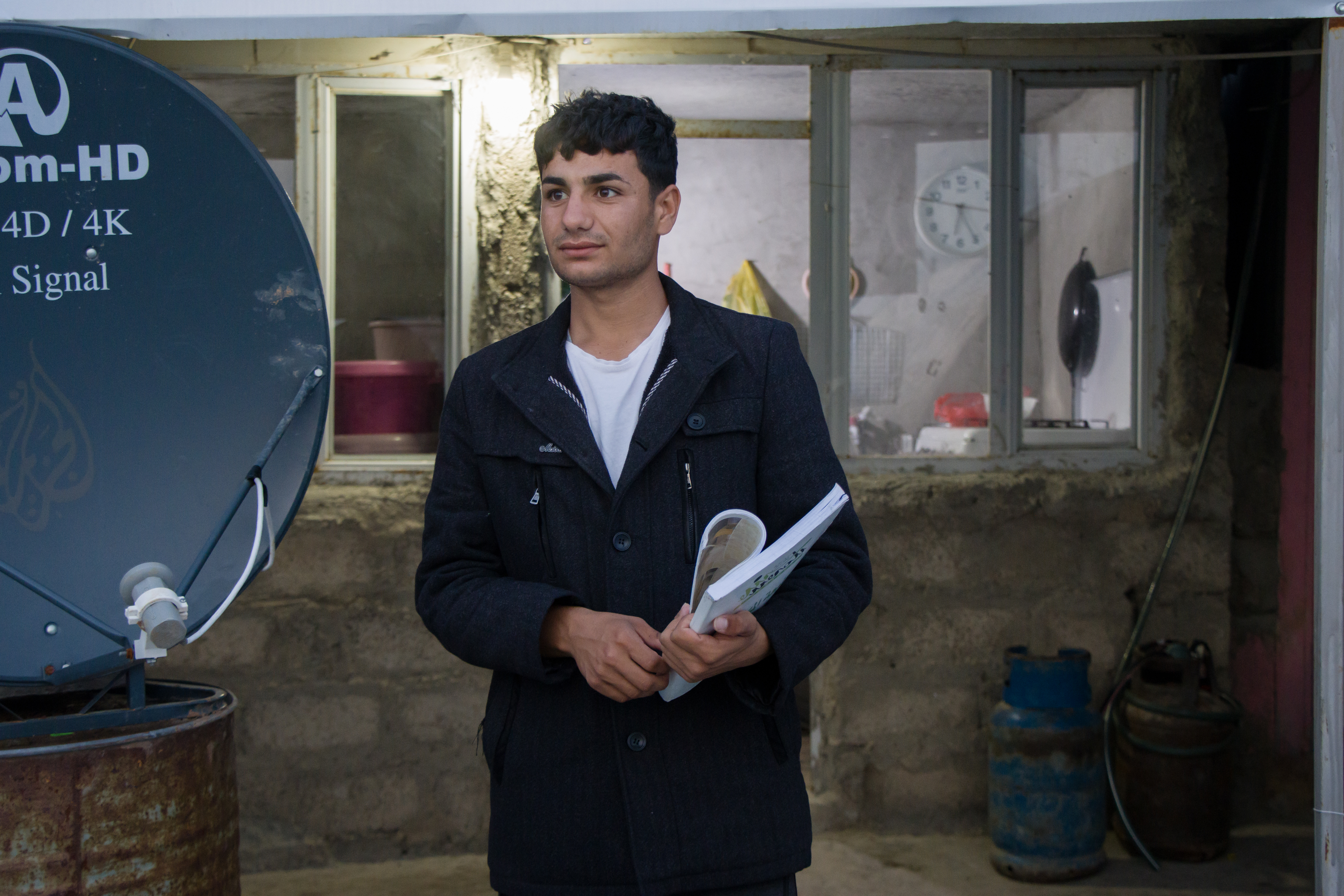 Nazar in front of a small kitchen his family built after years of living in Kabartu