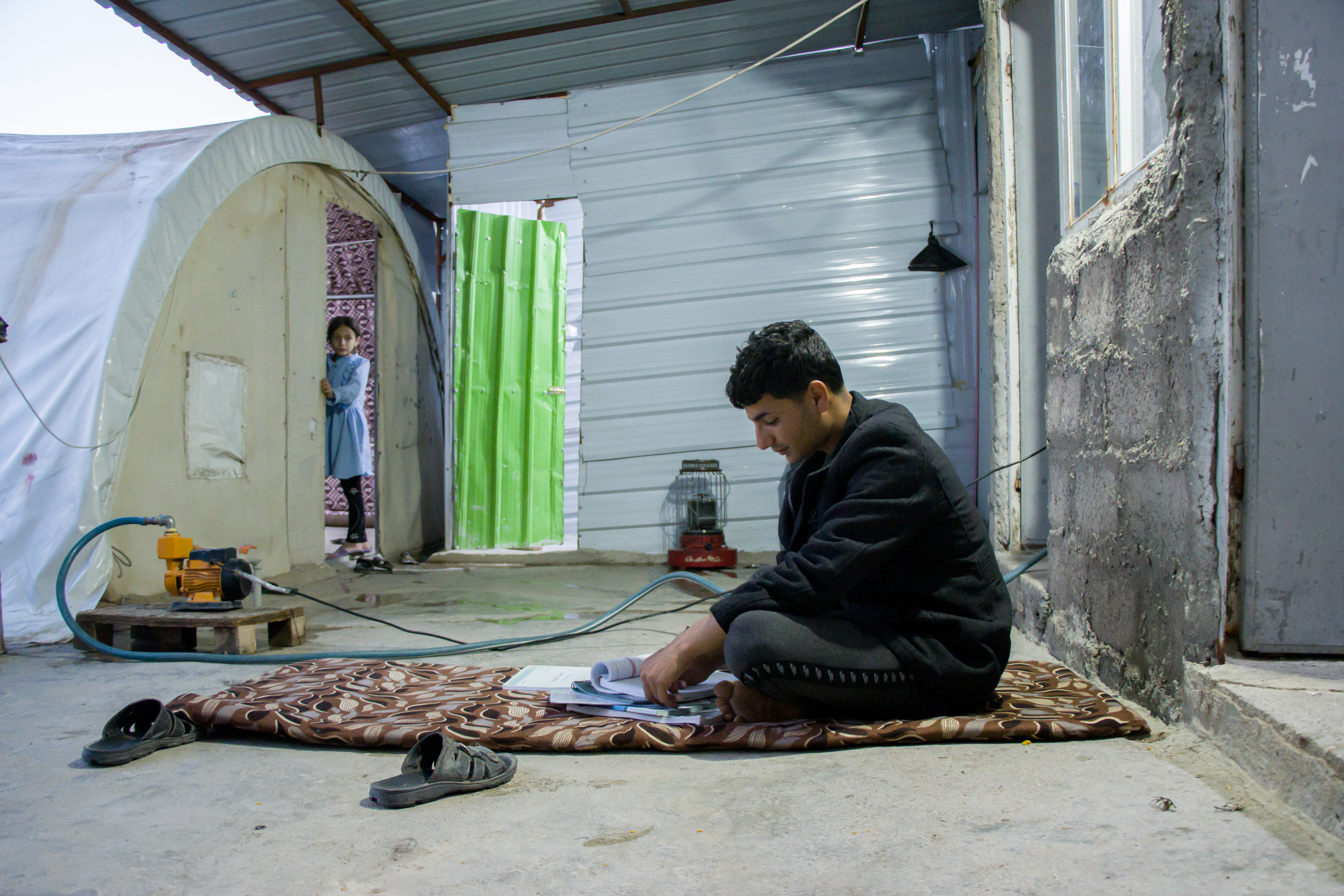 Nazar doing his homework next to the family tent. In the spring, some residents will try to get to Europe. But he wouldn't go, saying it is too dangerous, and that he must look after his family