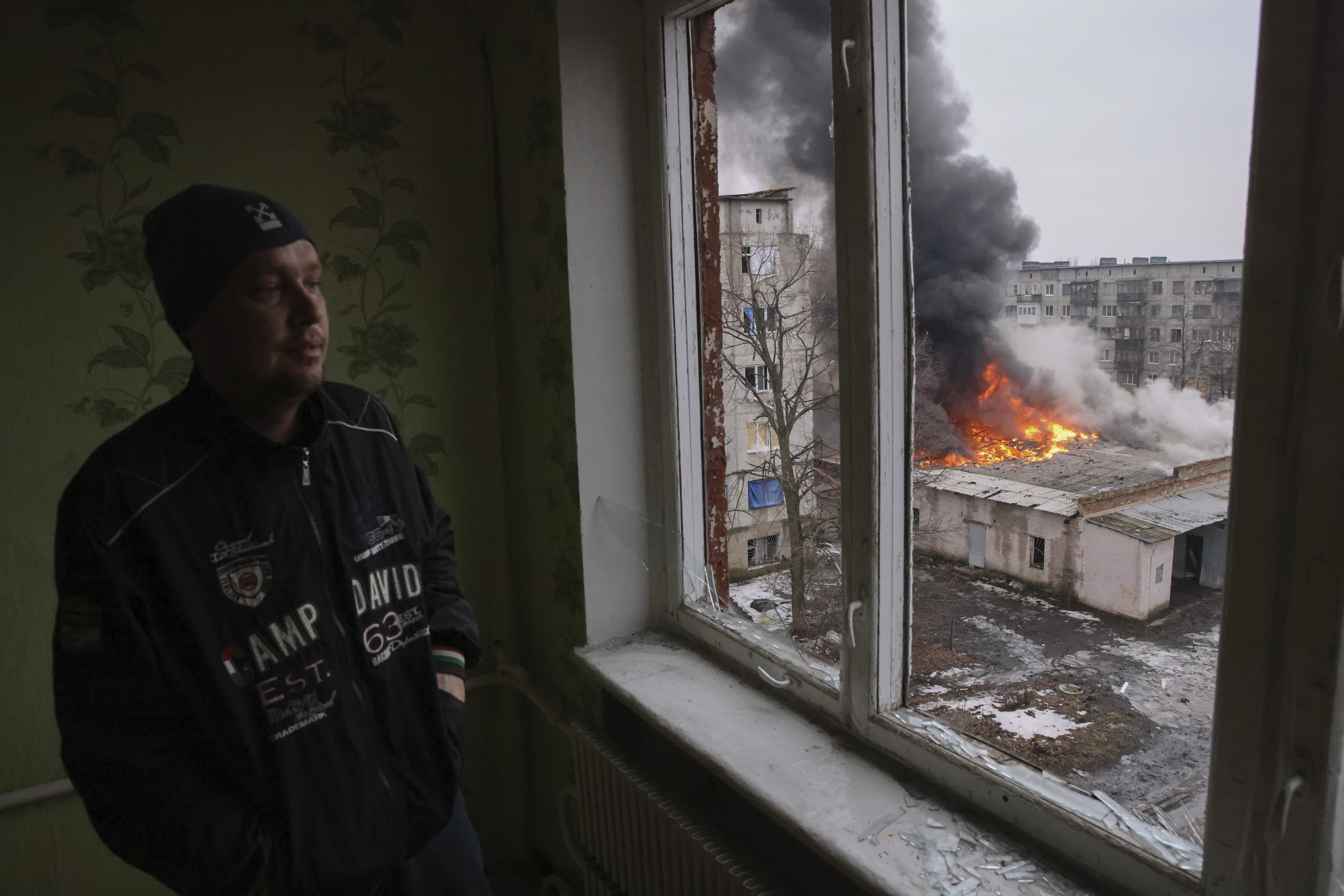 A man looks out to a burning building.