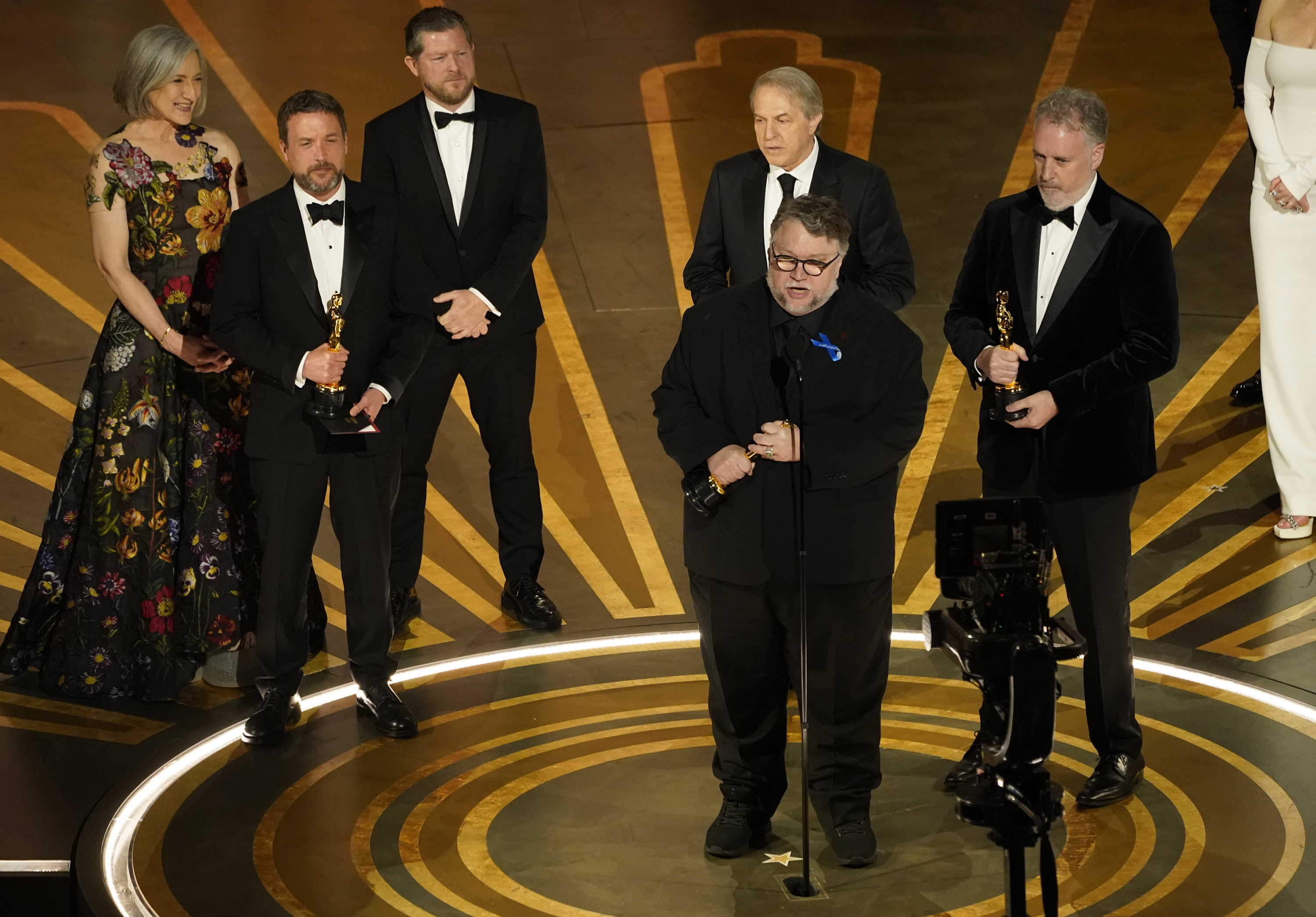Guillermo del Toro (centre) accepts a win for his stop-motion version of Pinocchio