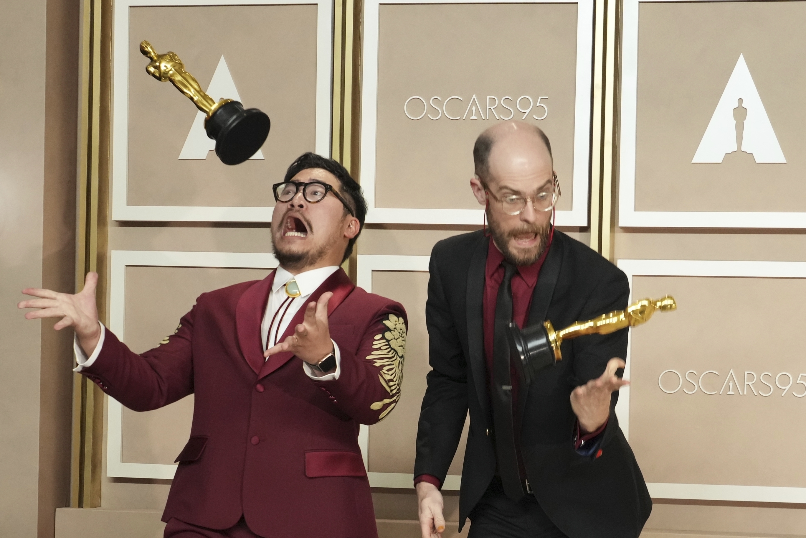 Daniel Kwan, left, and Daniel Scheinert get playful with their trophies for best director