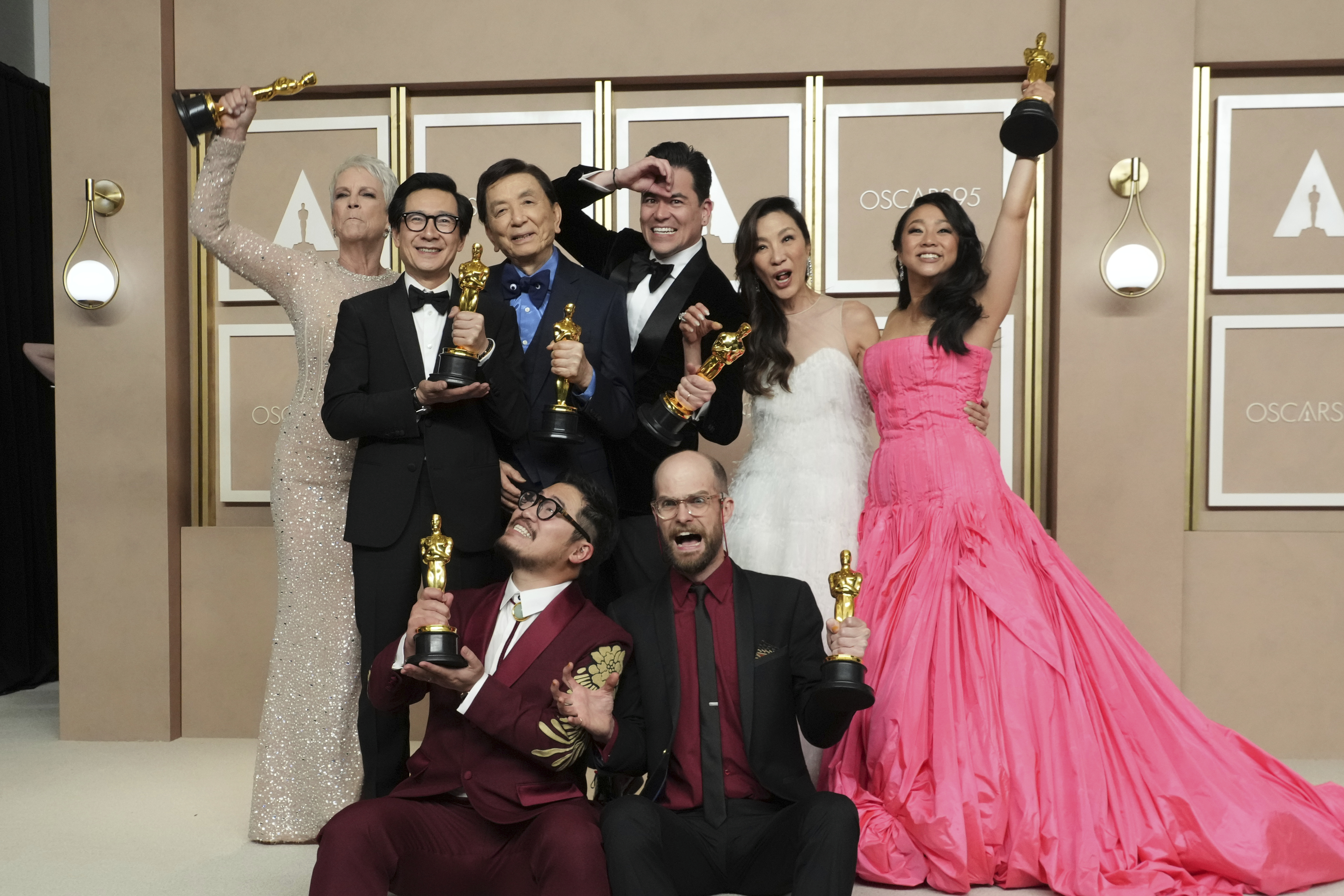 The cast of Everything Everywhere All at Once — from the top left, Jamie Lee Curtis, Ke Huy Quan, James Hong, Jonathan Wang, Michelle Yeoh and Stephanie Hsu — celebrate with directors Daniel Kwan and Daniel Scheinert, seated below