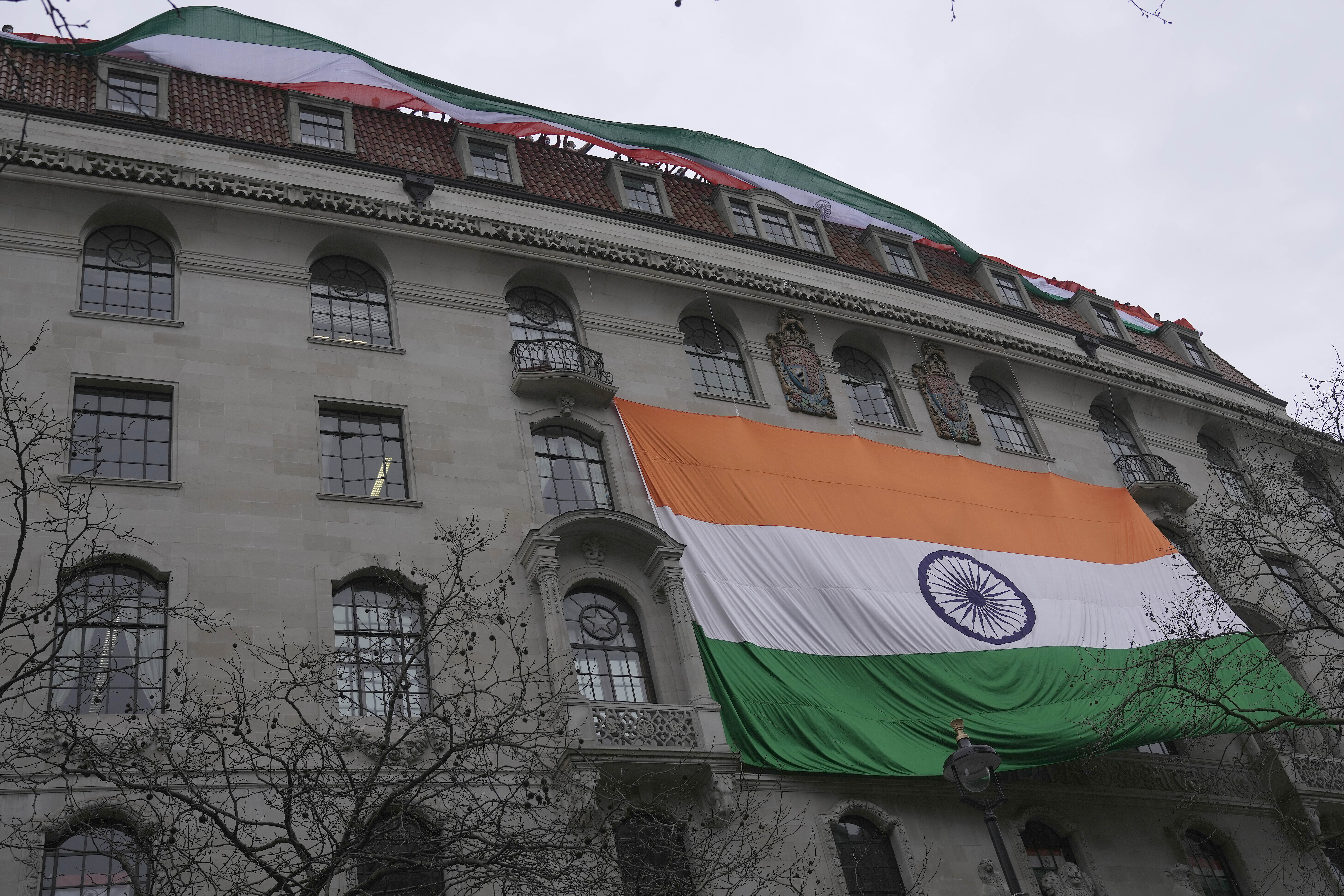People show an Indian flag from the roof of the Indian High Commission as alleged supporters of Khalistan movement demonstrate on the streets in London