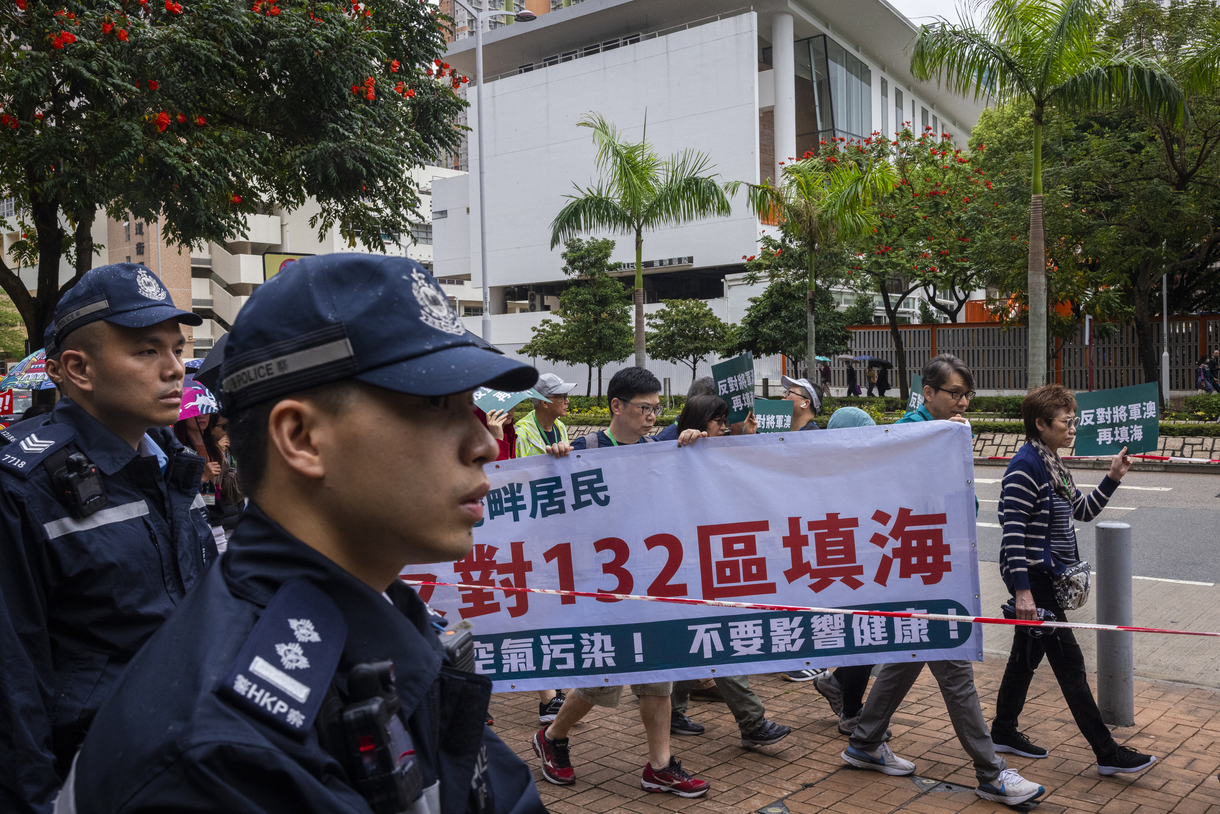 Police watch protesters walking within a cordon wearing tags during a rally in Hong Kong
