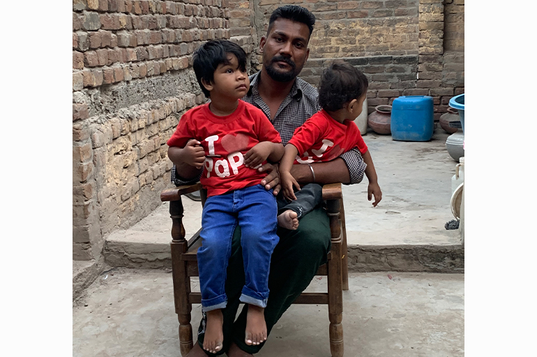 A photo of a man sitting with his two sons sitting on his lap.
