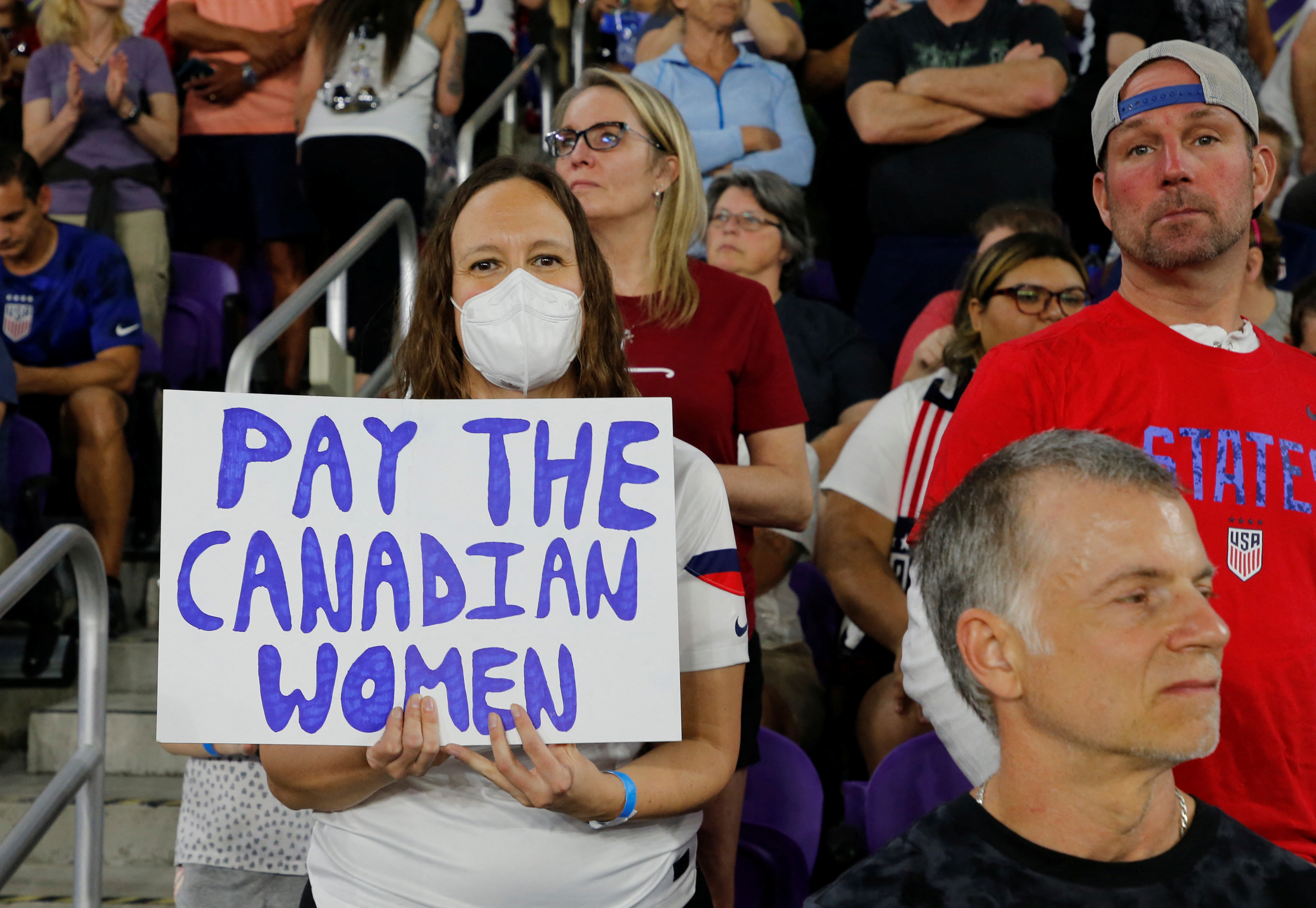 Guests hold signs in support of the Canadian National Women's Soccer Team