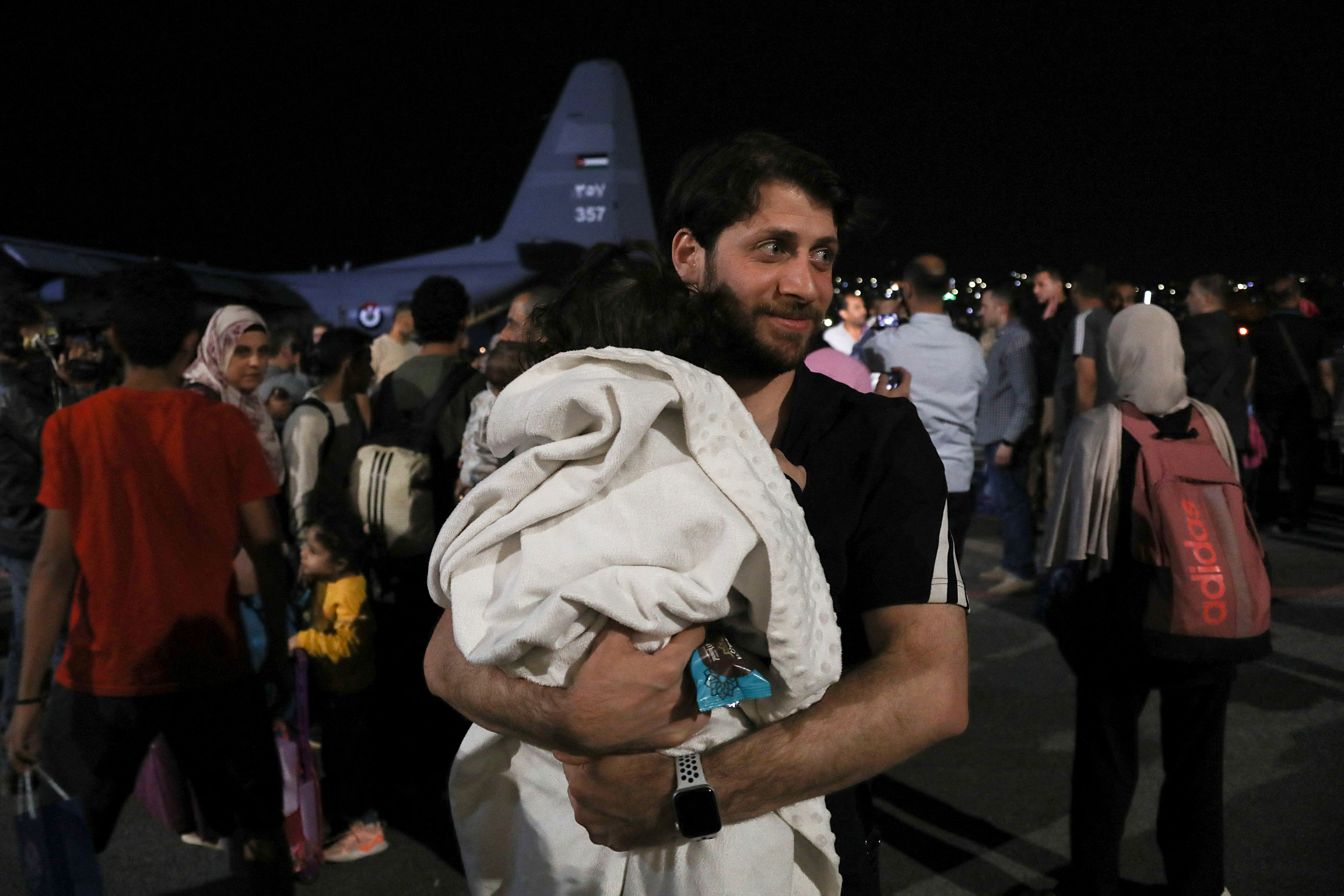 Man holding a sleeping baby smiles