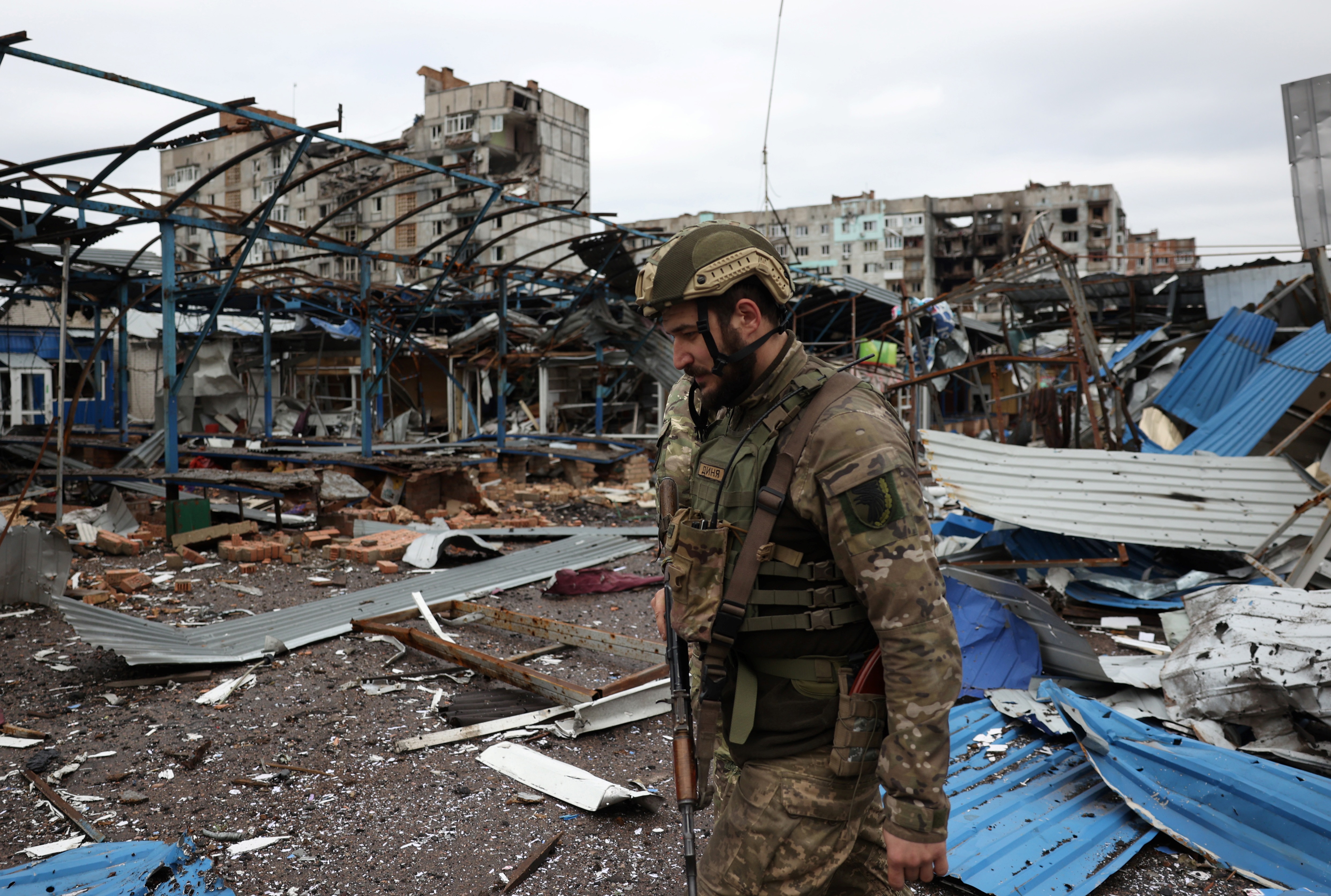 A Ukrainian serviceman walks near residential buildings damaged by shelling in the front-line city of Bakhmut, in the Donetsk region
