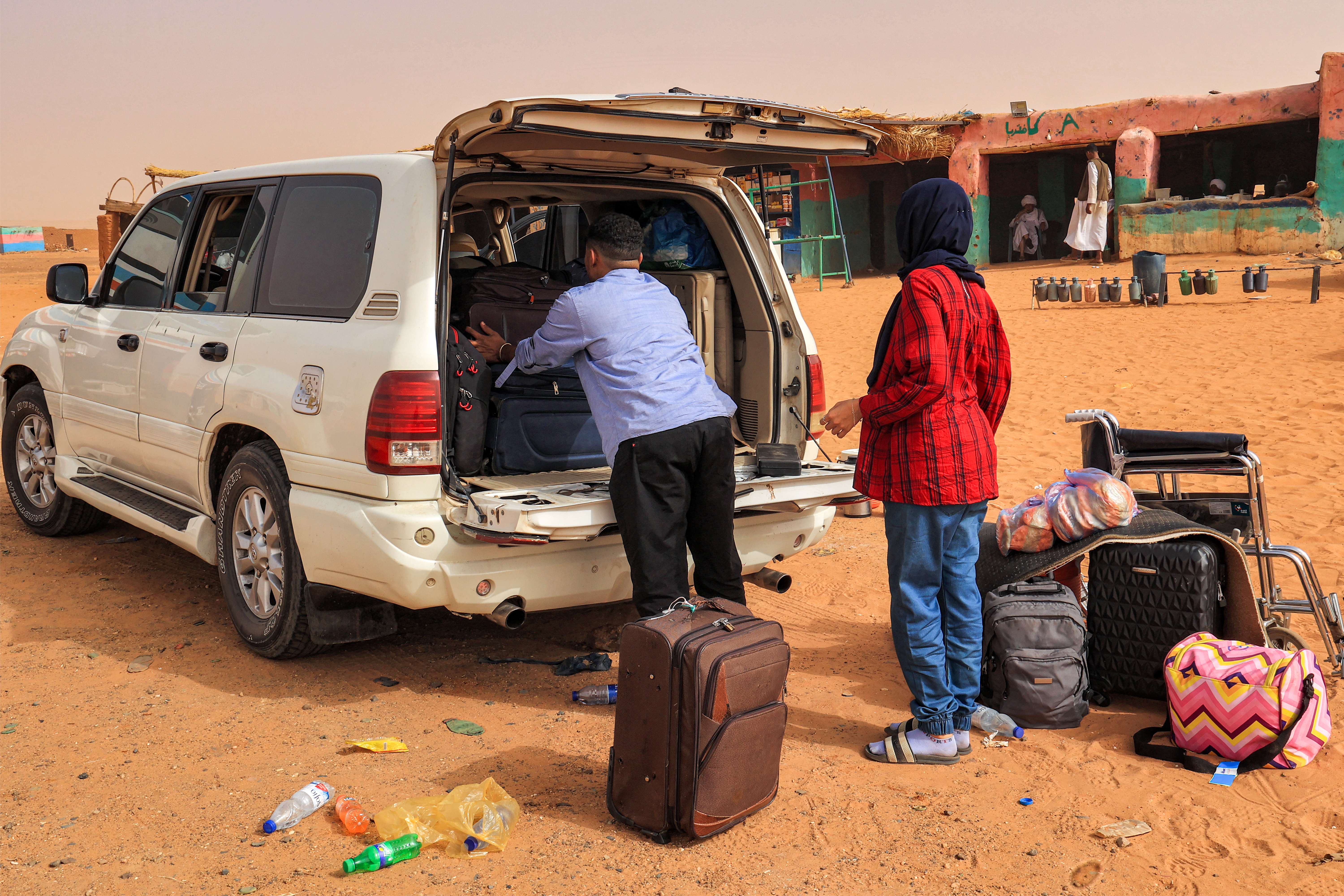 Passengers take out luggage as they disembark from a vehicle at a rest point by a desert road at al-Gabolab in Sudan's Northern State, about 100 kilometres northwest of the capital, on April 25, 2023.